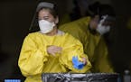 Elizabeth Santoro, a medic with the Minnesota Air National Guard 133rd Medical Group, tossed her gloves after administering a COVID-19 test Saturday a