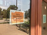 An orange laminated sign on a glass door reads "Sorry, the internet is not working" with a sad-face emoticon.