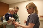 Anna Calcote repositioned a band aid on her son, Weston, 1, after he braved his 12-month series of shots, including the MMR vaccine, at the Children's