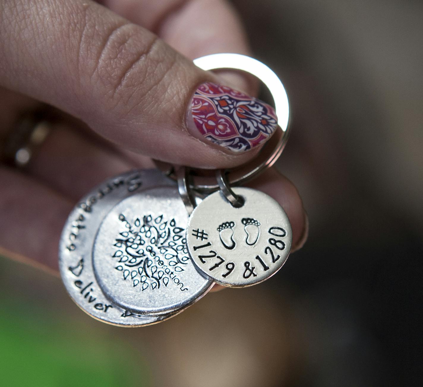 Claire Nielsen holds a keychain given to her by Growing Generations, the surrogacy agency that matched her with parents in need, at her home in Maple Grove June 9, 2015. The keychain reads "Surrogates Deliver Dreams," and the numbers represent the babies she carried and birthed for a couple. (Courtney Perry/Special to the Star Tribune)