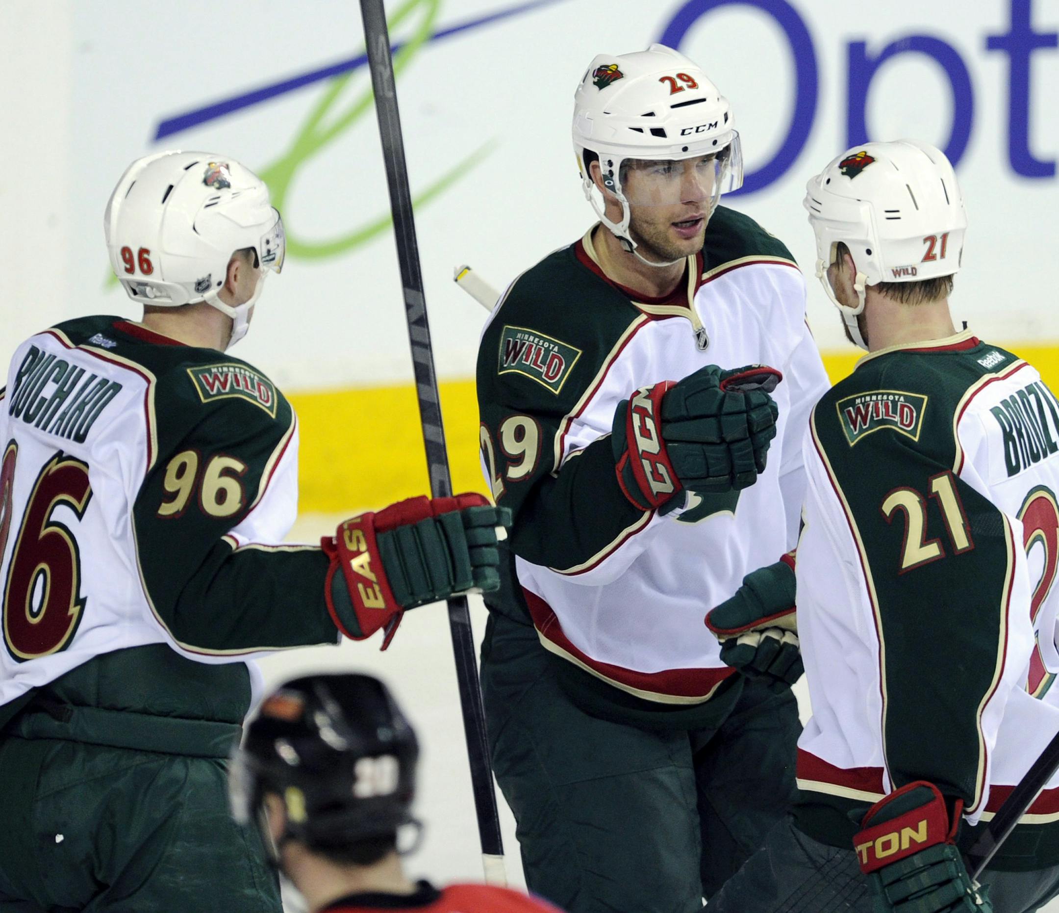 Minnesota Wild's' Jason Pominville, center, celebrates his goal against the Calgary Flames with Pierre-Marc Bouchard, left, and Kyle Brodziak during the second period of an NHL hockey game in Calgary, Alberta, Monday, April 15, 2013. (AP Photo/The Canadian Press, Larry MacDougal)