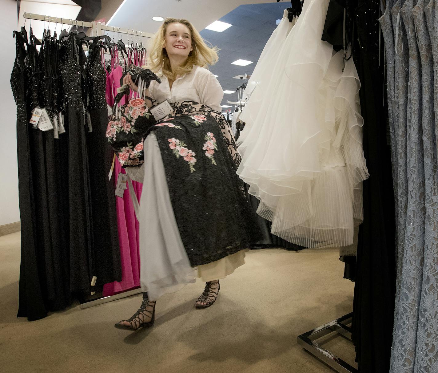 Ali-Jae Nicolai, 17, a junior at New Prague High School, carries a selection of dresses while shopping for prom dresses at Macy's at the Mall of America.