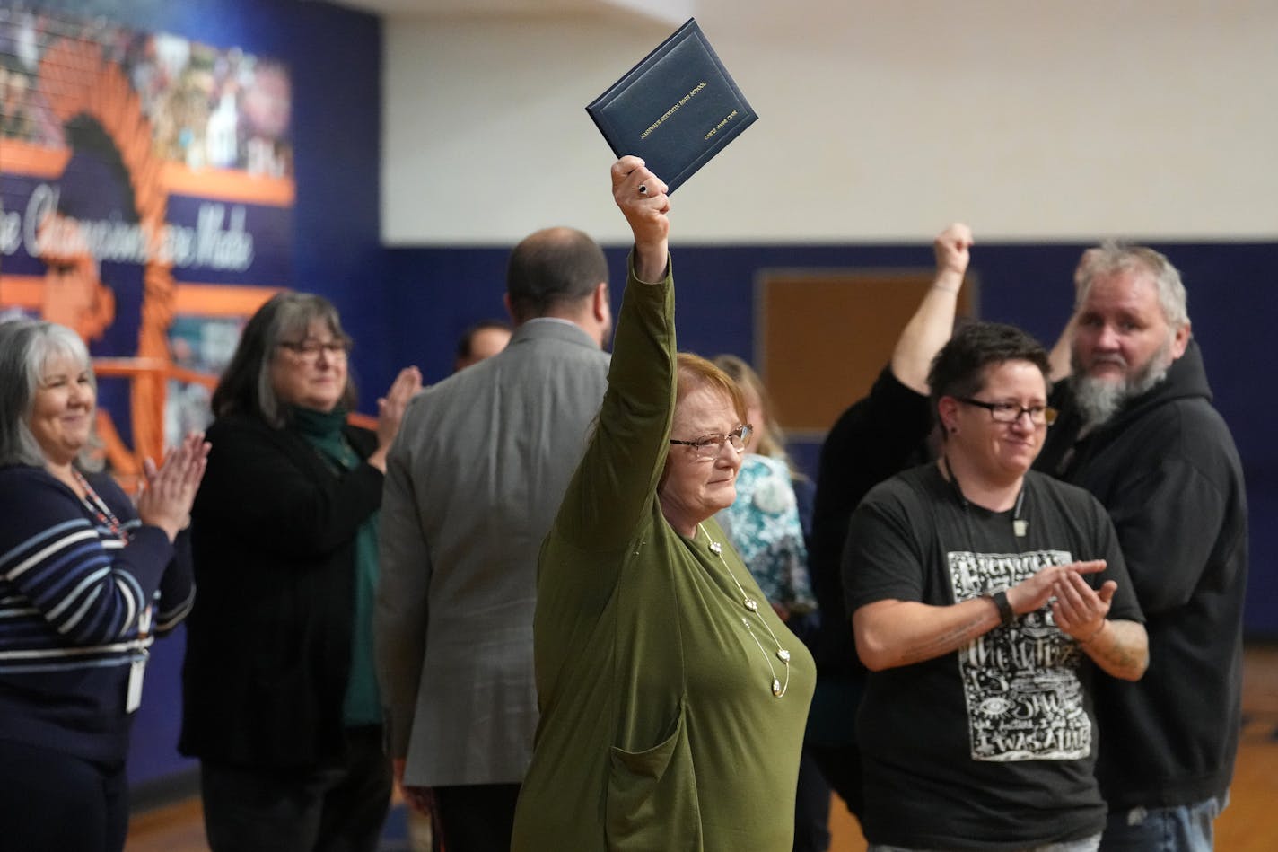 Bonnie McBride held up a posthumous diploma for her mother, Carole McBride, who in 1961 was denied a signed diploma because she wasn't able to meet the gym requirement due to her cerebral palsy, during a ceremony to honor her Tuesday, Dec. 12, 2023 at Nashwauk-Keewatin High School in Nashwauk, Minn. ] ANTHONY SOUFFLE • anthony.souffle@startribune.com