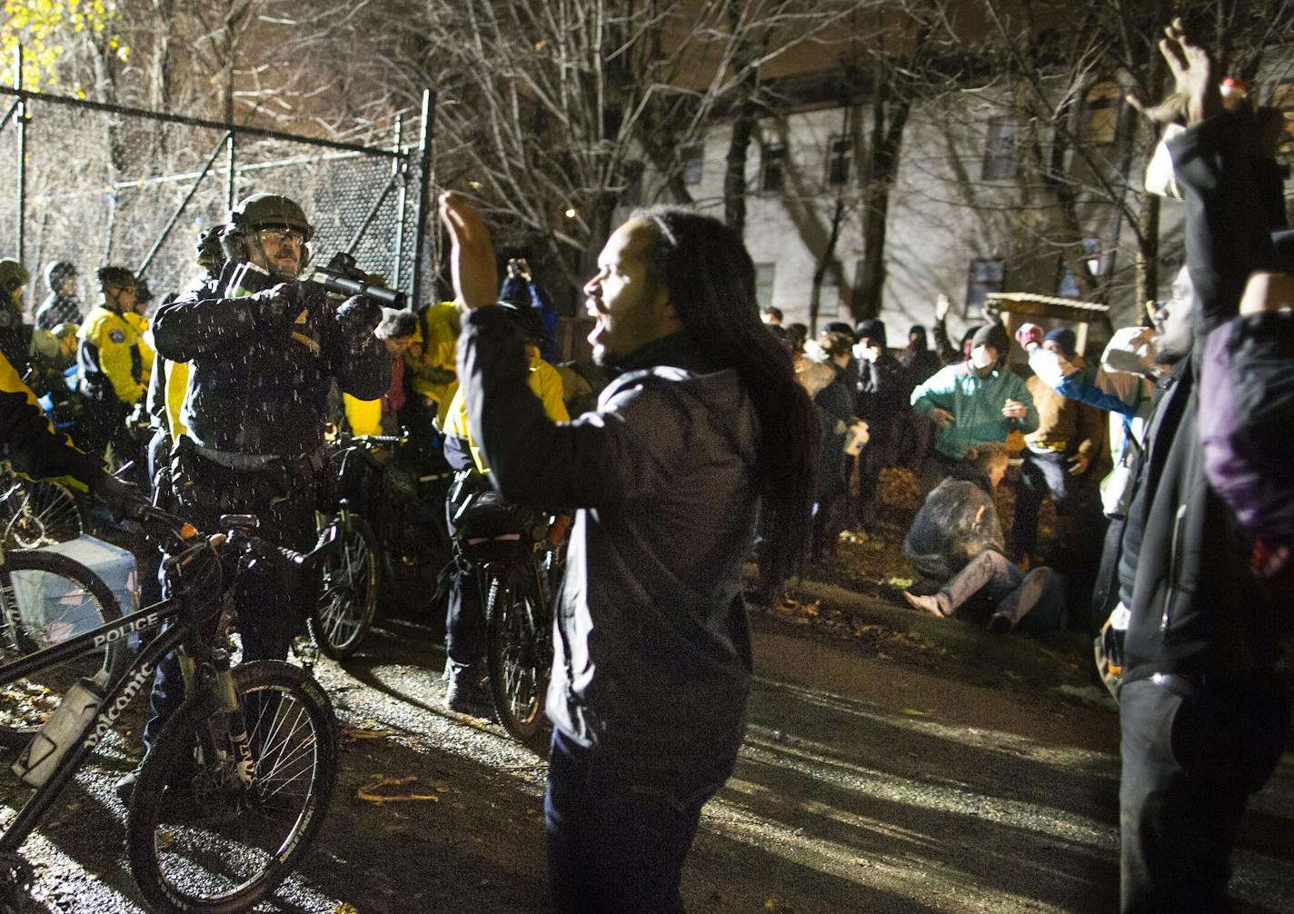 In this Wednesday, Nov. 18, 2015 photo, Jeremiah Ellison, center right, son of U.S. Rep. Keith Ellison, stands near police during a protest at the Minneapolis Police Department 4th Precinct building in Minneapolis. People were protesting the fatal shooting of Jamal Clark by Minneapolis police on Sunday. (Renee Jones Schneider/Star Tribune via AP) MANDATORY CREDIT; ST. PAUL PIONEER PRESS OUT; MAGS OUT; TWIN CITIES LOCAL TELEVISION OUT ORG XMIT: MIN2015111919382889