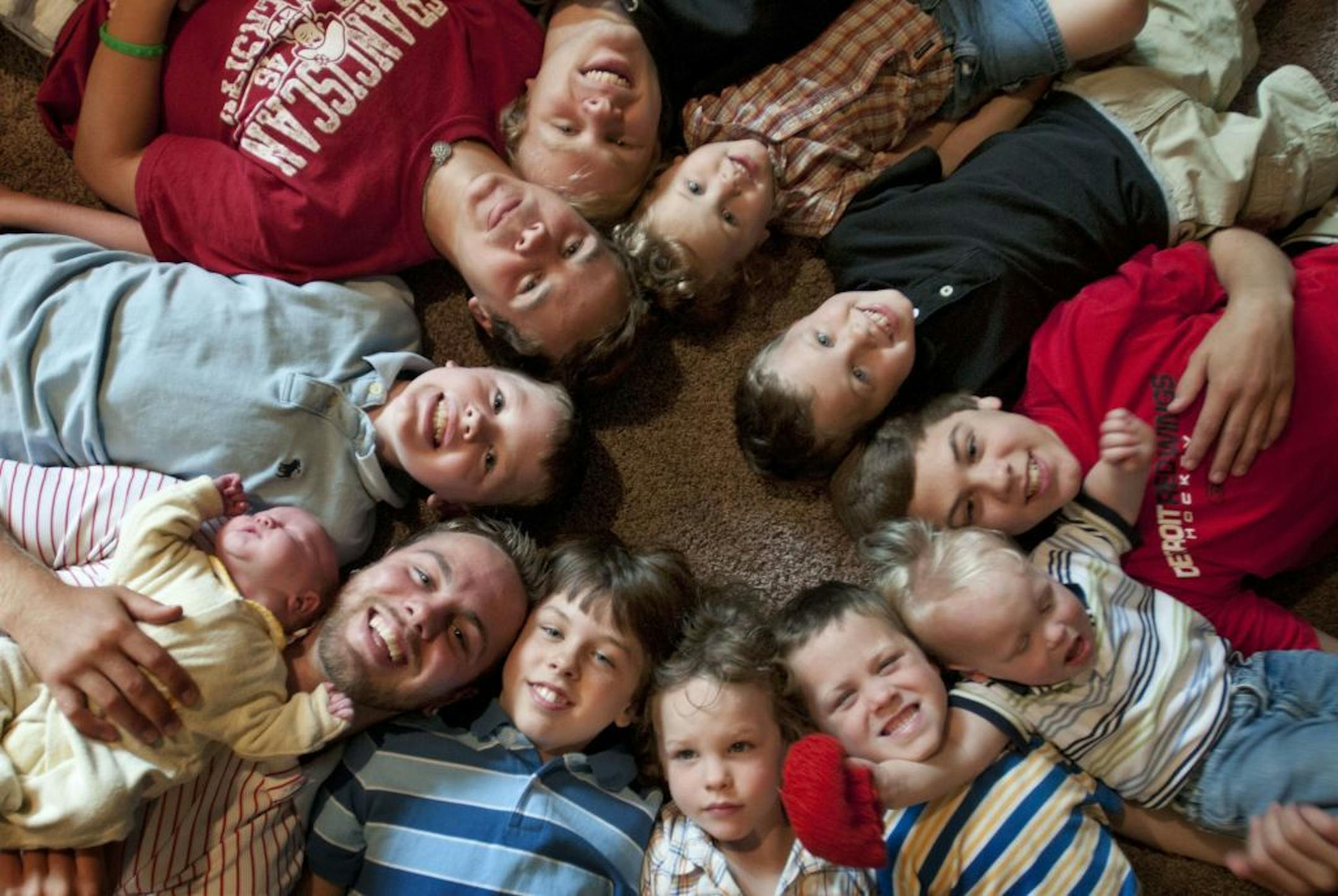 FILE - In this Aug. 6, 2013 file photo, the 12 Schwandt brothers pose for a photo in their home in Rockford, Mich. Clockwise from bottom left are, Tyler, 21, holding Tucker, 2 days, Vinny, 10, Drew, 16, Zach, 17, Charlie, 3, Calvin, 8, Brandon, 14, Luke, 19 months, Gabe, 6, Wesley, 5 and Tommy, 11. Jay and Kateri Schwandt, a western Michigan couple with 12 sons is expecting baby No. 13 and they say they'll be surprised if their all-boy streak is snapped. The Grand Rapids Press reports that Schwa