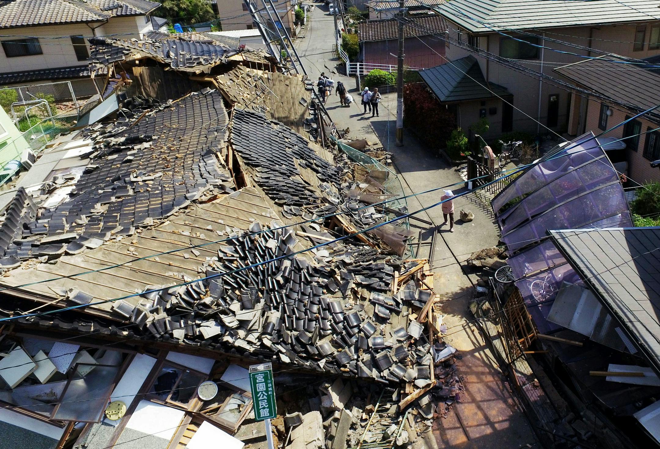 This aerial view shows damaged houses in Mashiki town, Kumamoto prefecture, southern Japan, Friday, April 15, 2016, a day after a magnitude-6.5 earthquake. More than 100 aftershocks from Thursday night's magnitude-6.5 earthquake continued to rattle the region as businesses and residents got a fuller look at the widespread damage from the unusually strong quake, which also injured about 800 people. (Koji Harada/Kyodo News via AP) JAPAN OUT, MANDATORY CREDIT