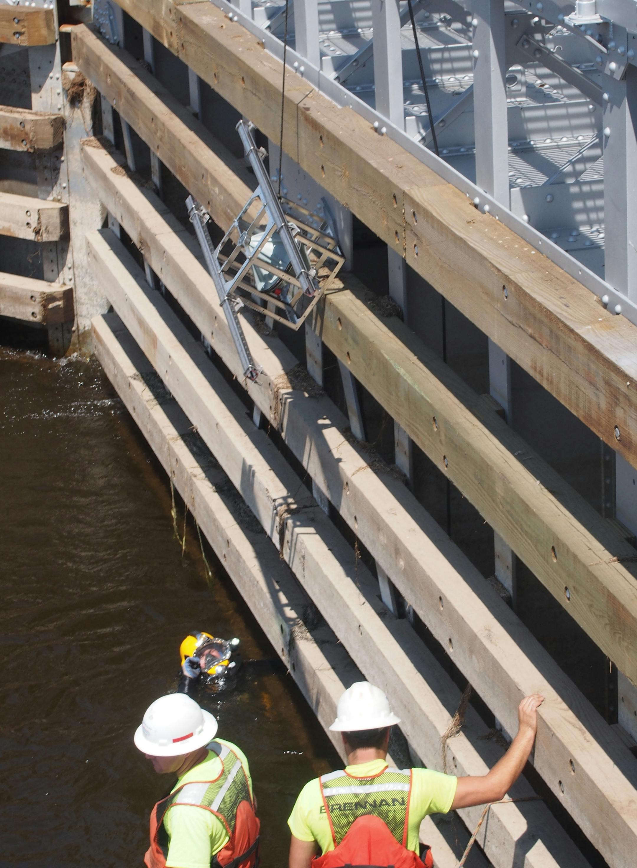 Workers lowered an underwater speaker to a scuba diver recently so it could be attached at Lock 8 on the Mississippi River near Genoa, Wis. The experimental system is designed to repel Asian carp.
