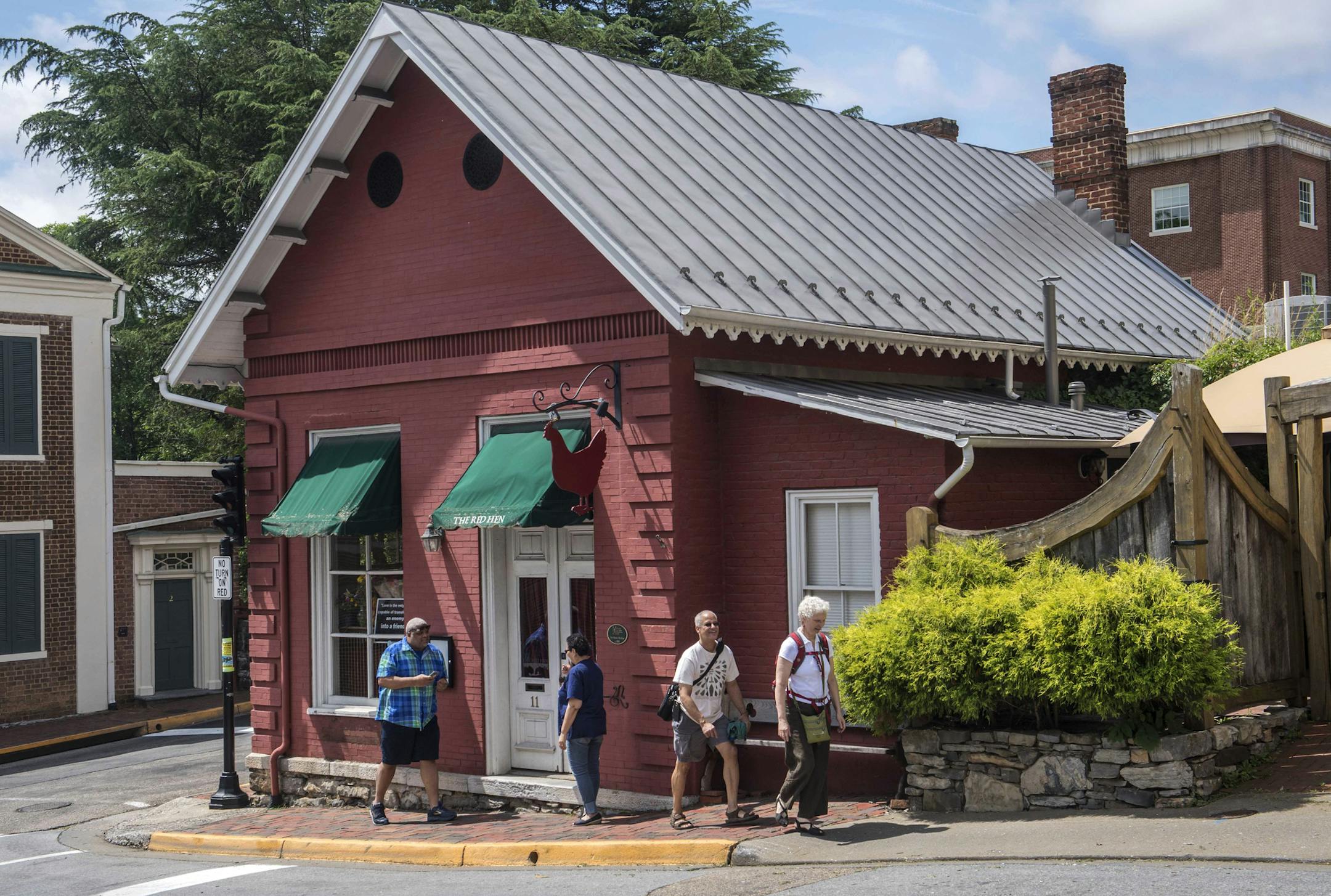 People walk past the Red Hen restaurant in Lexington, Va., Wednesday, June 27, 2018. The co-owner of the Virginia restaurant that refused to serve White House press secretary Sarah Huckabee Sanders has resigned from a local business group. (AP Photo/Don Petersen)