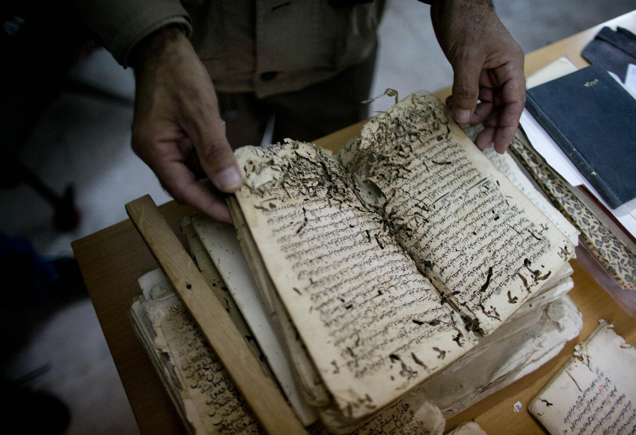 In this photo taken on Monday, Jan. 27, 2014, an employee shows an old manuscript at the al-Aqsa mosque compound library in Jerusalem. The library has a collection of some 4,000 old manuscripts with about a quarter considered in poor condition. Half of the books are already undergoing restoration funded by the Waqf, Jordanís Islamic authority which manages the holy site, and with assistance from UNESCO. (AP Photo/Dusan Vranic)