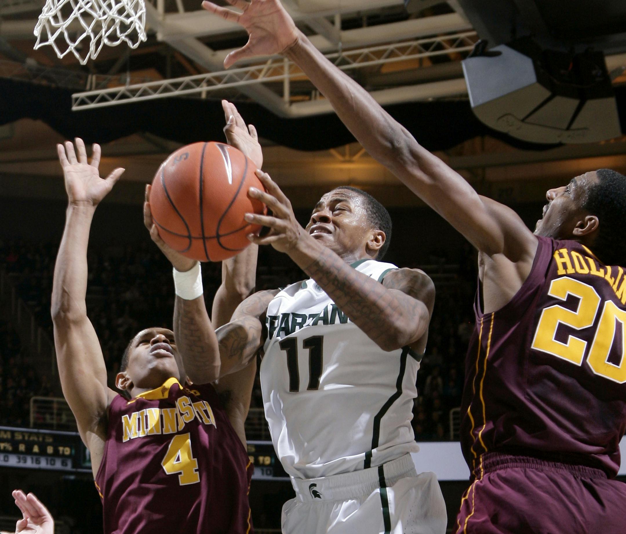 Michigan State's Keith Appling (11) puts up a shot between Minnesota's DeAndre Mathieu (4) and Austin Hollins (20) during overtime of an NCAA college basketball game, Saturday, Jan. 11, 2014, in East Lansing, Mich. Appling led Michigan State with 24 points in an 87-75 overtime win. (AP Photo/Al Goldis)