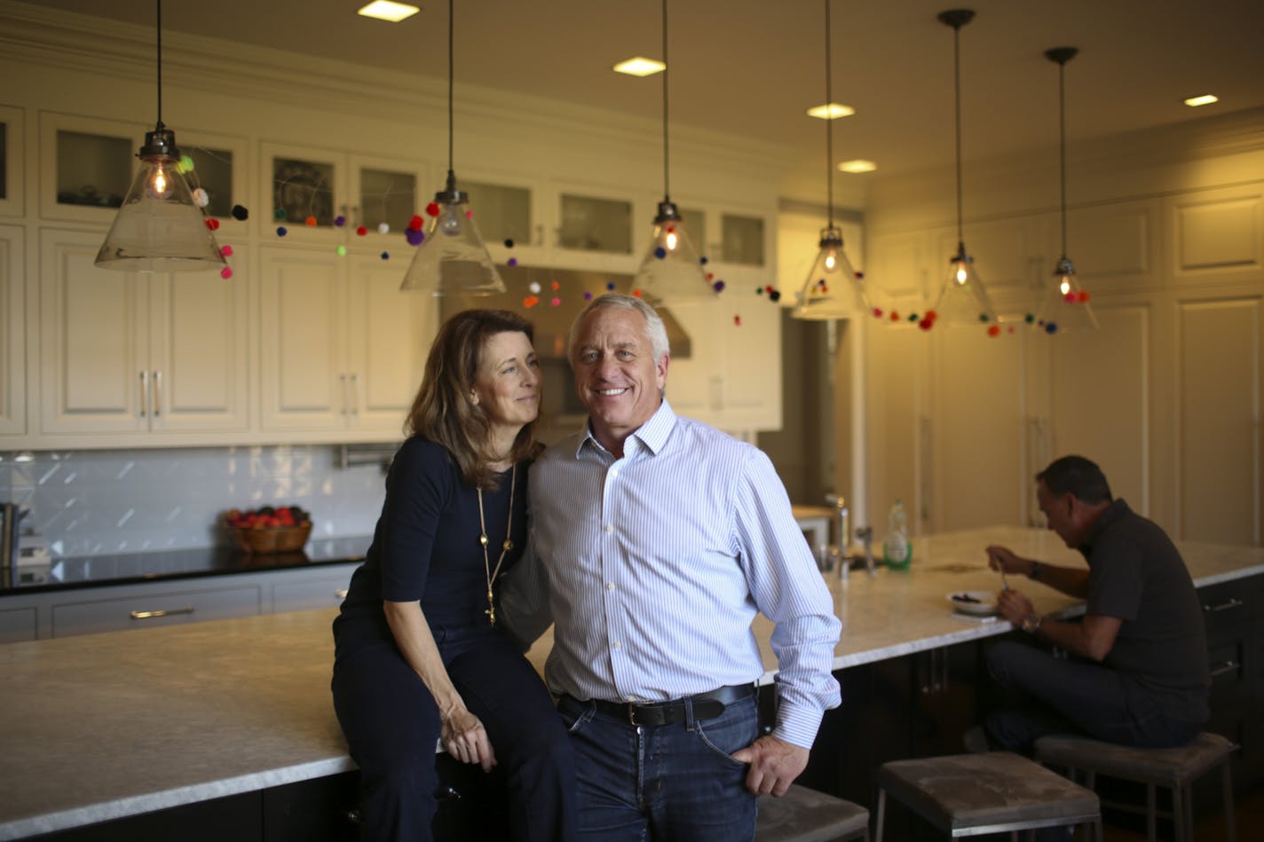 Greg and Kathy LeMond in the kitchen of their home in Hamel. A friend visiting from France is eating some leftover Chinese food at the island behind them.