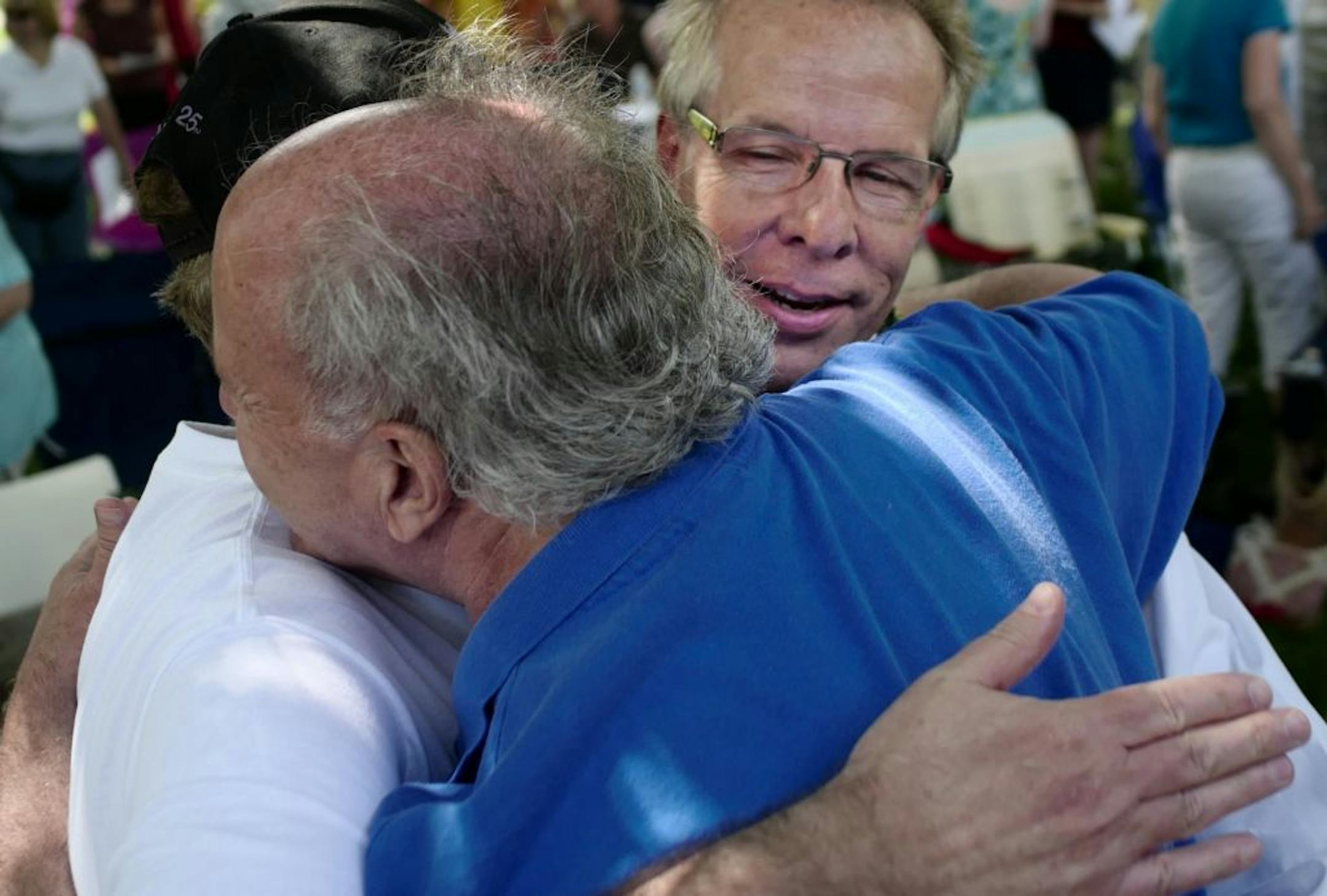 James Knapp, hidden, Jerry Rubino, blue shirt, and pastor Richard Buller hugged during the extending of friendship during the morning service at Brookview Park, where the LGBT community in Golden Valley celebrated Pride weekend but also remembered the tragedy in Orlando that took the lives of 50 people.