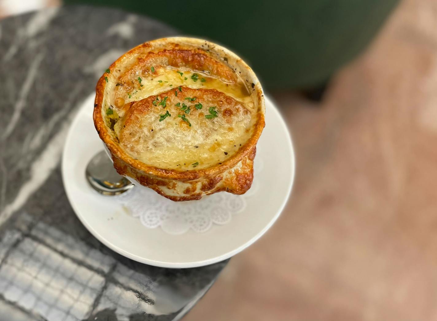 A white crock of cheesy soup on a gray table