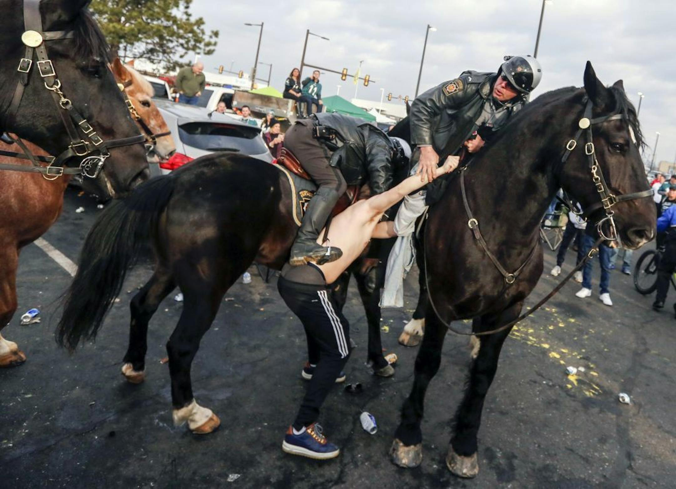 A fan is taken into custody after violence erupted in Parking Lot M as Philadelphia Police and Pennsylvania State Troopers on horseback tried to disperse fans who were tailgating hours before the Philadelphia Eagles were scheduled to host the Minnesota Vikings in the NFC championship NFL football game Sunday, Jan. 21, 2018, in Philadelphia.