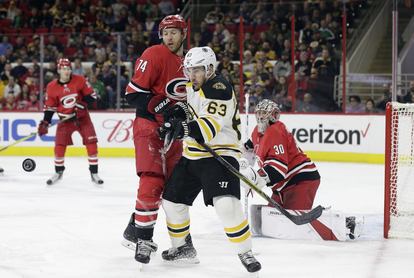 Boston Bruins' Brad Marchand (63) chases the puck with Carolina Hurricanes' Jaccob Slavin (74) as Hurricanes goalie Cam Ward keeps an eye on the puck during the first period of an NHL hockey game in Raleigh, N.C., Tuesday, March 13, 2018. (AP Photo/Gerry Broome)