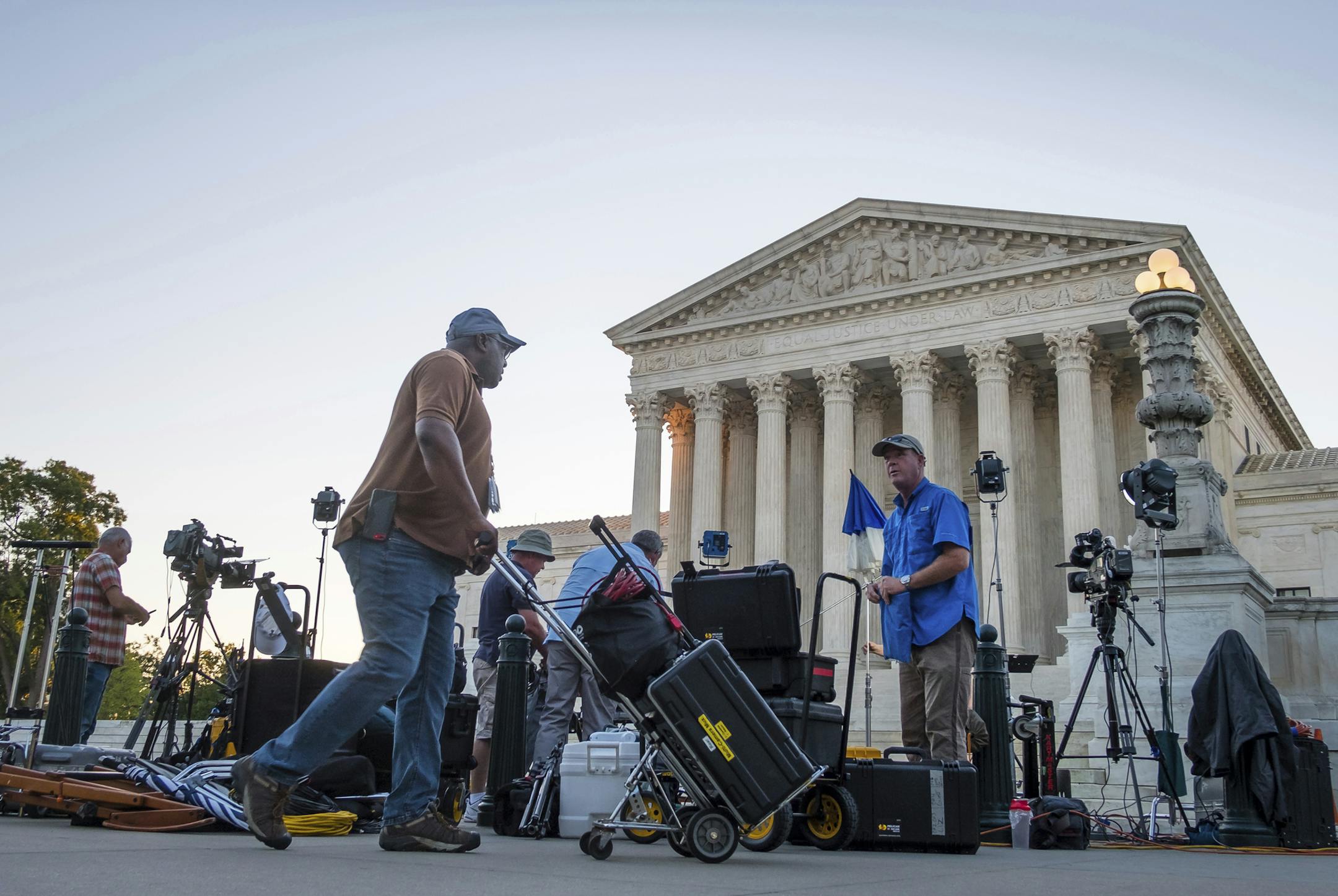 News crews set up in front of the U.S. Supreme Court early Monday morning, July 9, 2018, in Washington. President Trump is expected to announce his choice for Supreme Court Justice Monday evening. (AP Photo/J. David Ake)
