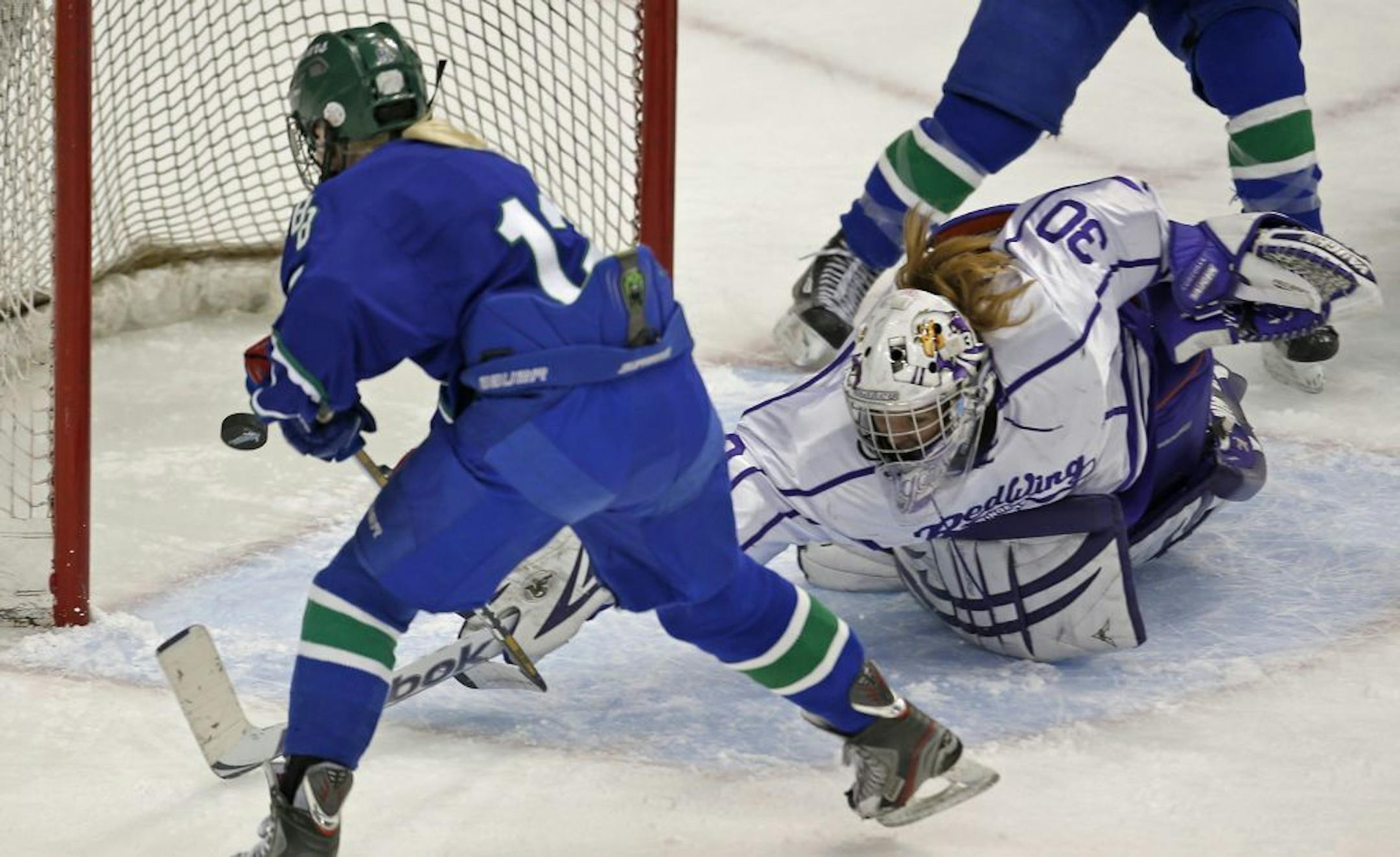 Minnesota State Girls Hockey Tournament Class 1A Semifinalsfinals, The Blake School vs. Red Wing 2/22/13. (left to right) Blake's Karlie Lund shot the puck past Red Wing goalie Ashley Corcoran for a score in the first period. Lund would go on to score a hat trick in the game against Red Wing.