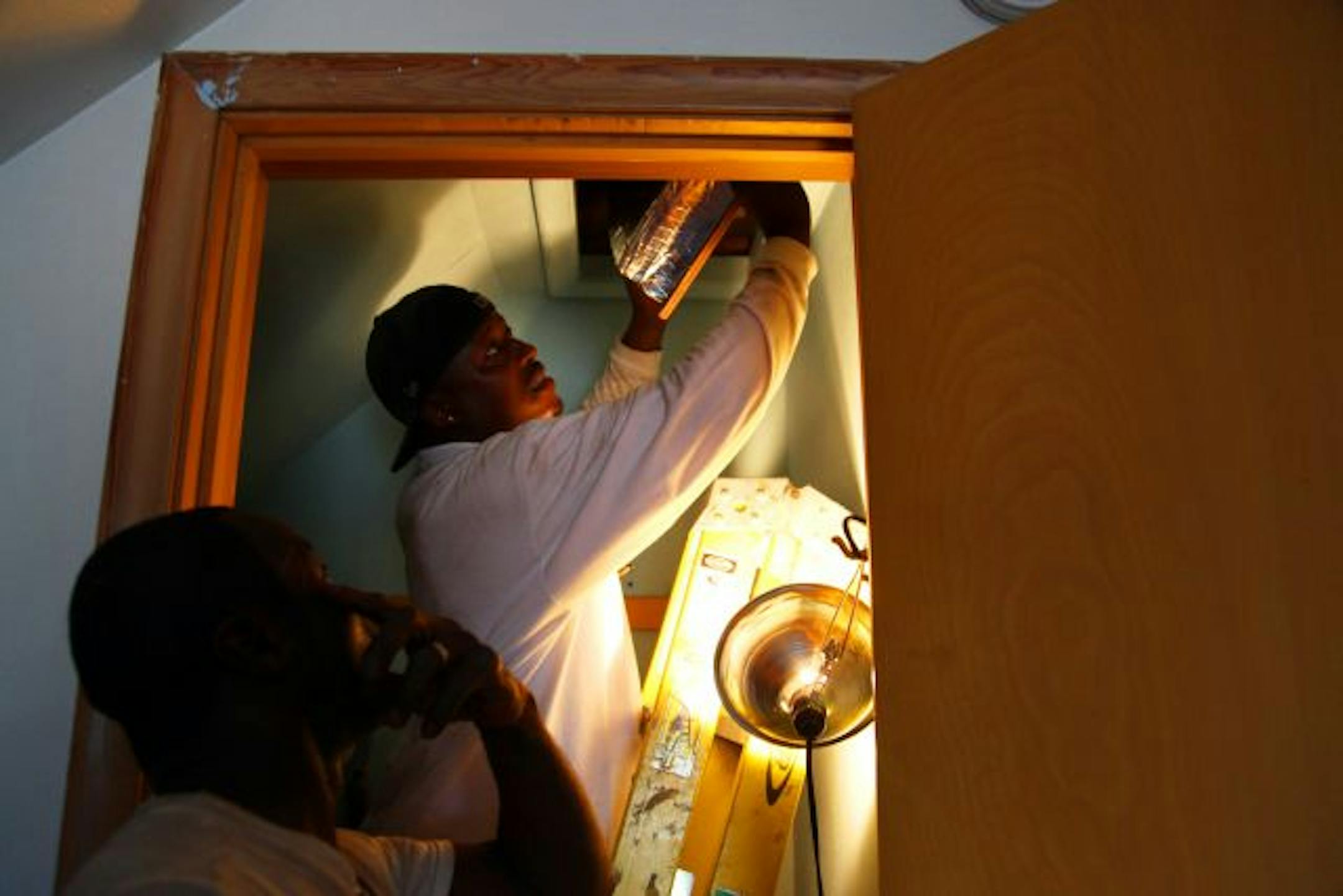 Michael Doss, right, installed an insulated hatch door in an attic at a house in St. Paul as coworker Ike Turner watched.