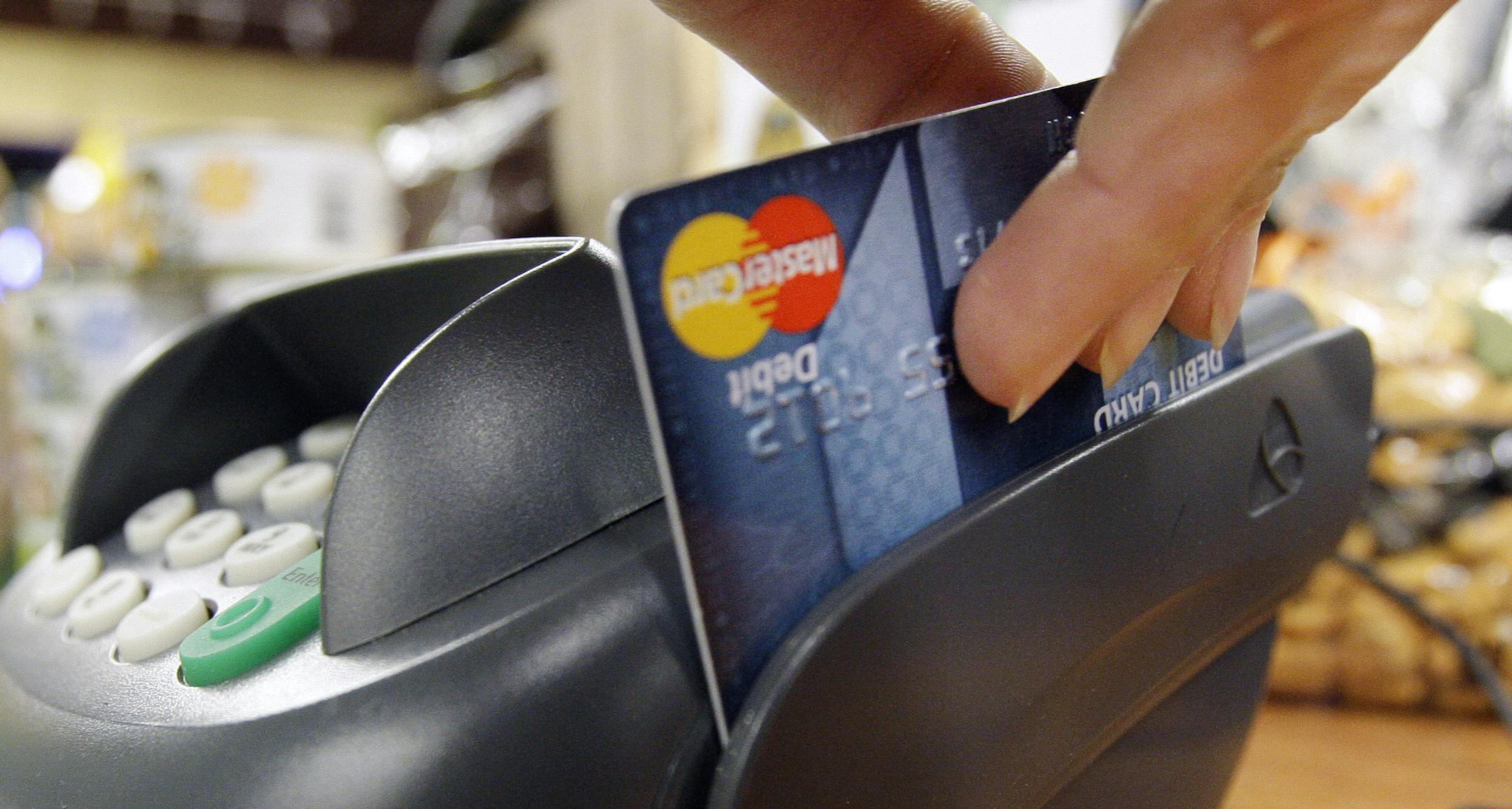 FILE - In this Nov. 2, 2009 file photo, a customer swipes a MasterCard debit card through a machine while checking-out at a shop in Seattle. For many, part of the strategy for keeping on budget includes a plan to leave the credit cards at home and use a debit card at the checkout. (AP Photo/Elaine Thompson, file) ORG XMIT: MIN2012112715572282