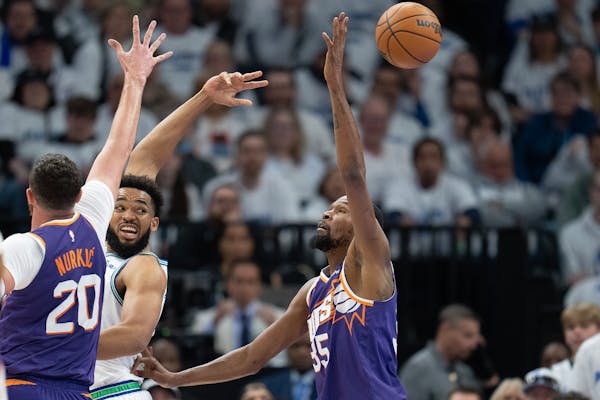 Timberwolves center Karl-Anthony Towns (32) passes the ball behind his head and past Suns center Jusuf Nurkic (20) and forward Kevin Durant (35) in th