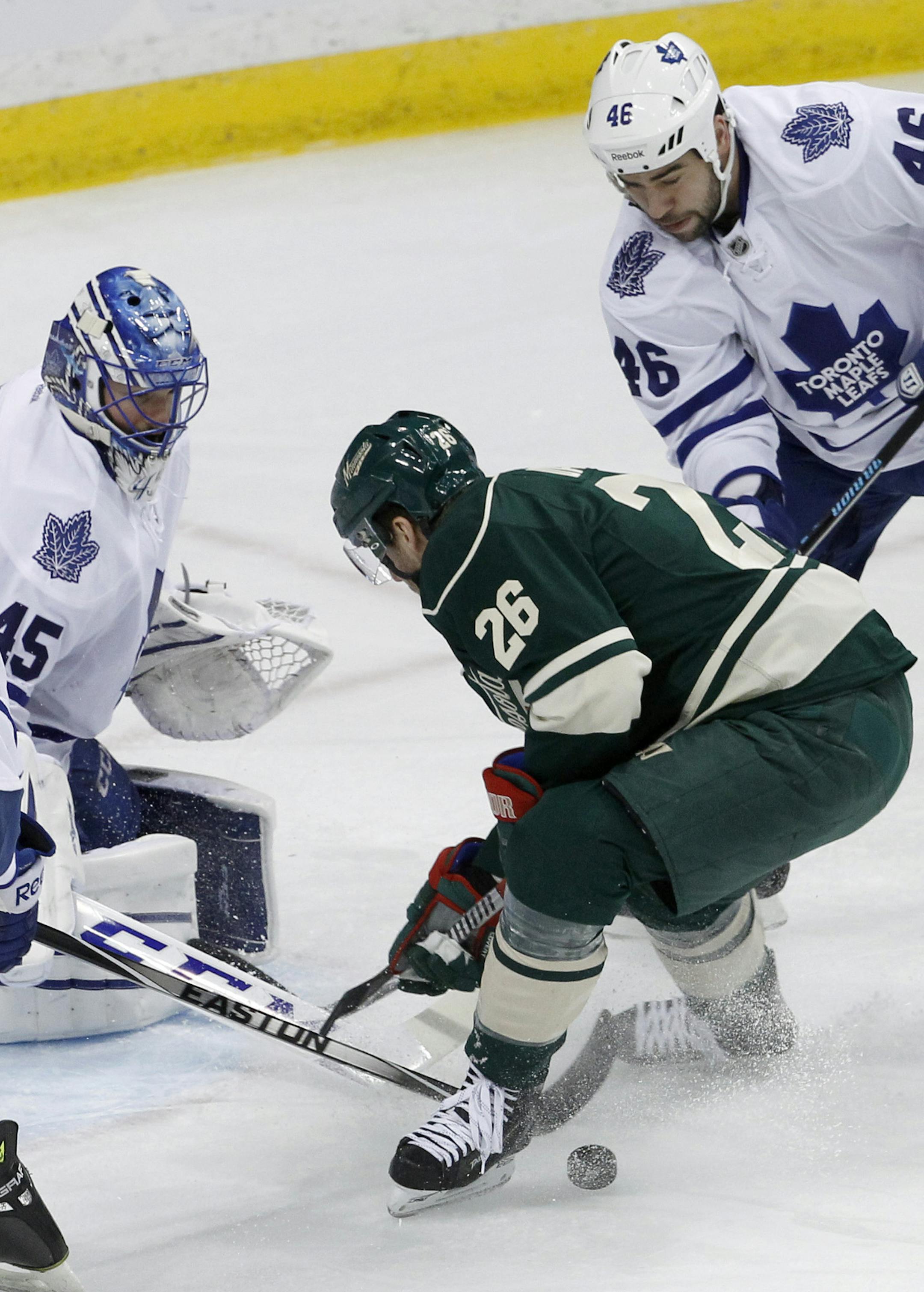 Toronto Maple Leafs goalie Jonathan Bernier (45) deflects a shot by Minnesota Wild left wing Thomas Vanek (26), of Austria, as Maple Leafs defenseman Roman Polak (46) watches during the first period of an NHL hockey game in St. Paul, Minn., Friday, Jan. 2, 2015. (AP Photo/Ann Heisenfelt)