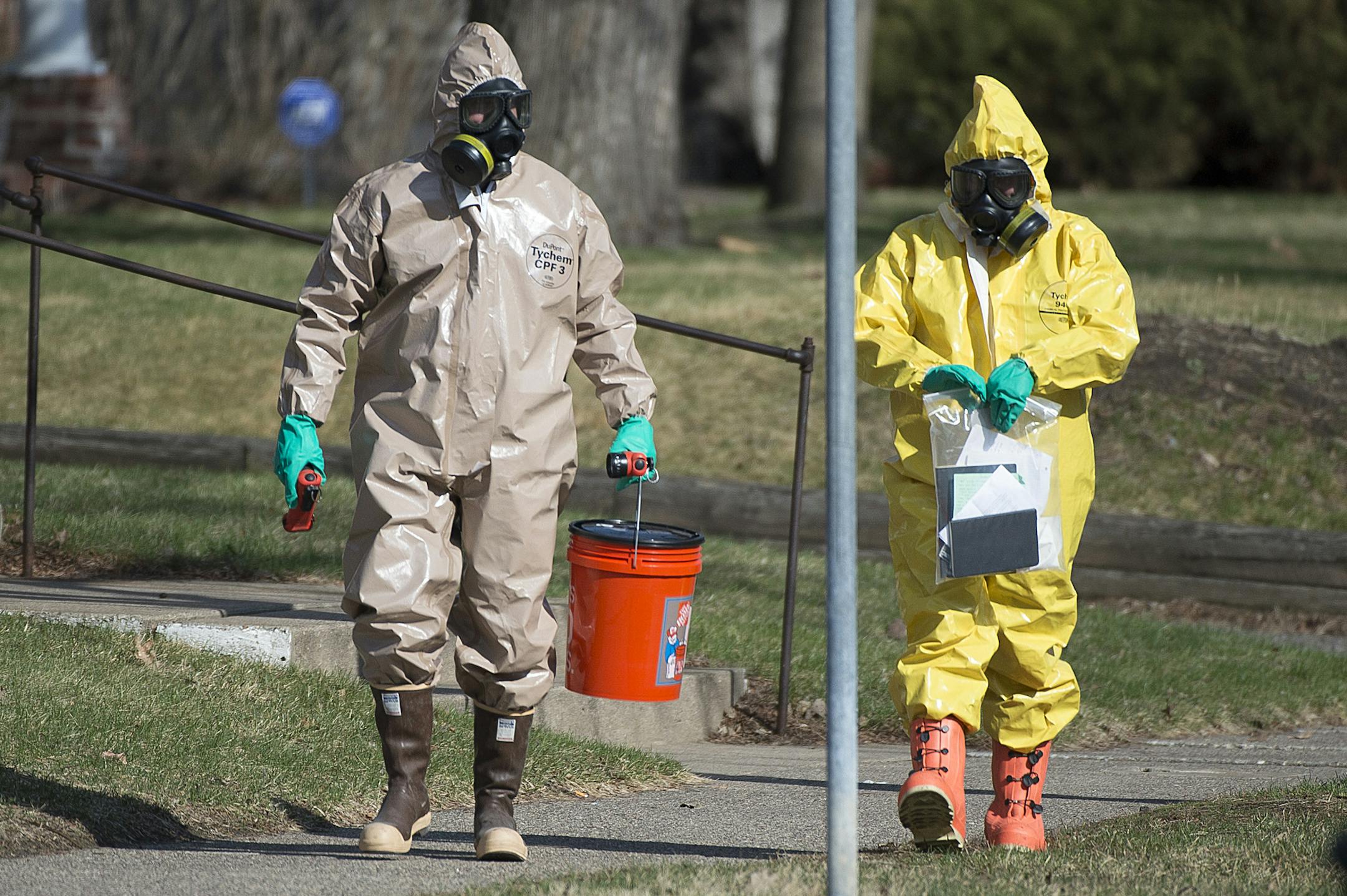 Hazardous material workers leave a residence carrying a bag of books and papers as wells as a bucket in the Marcy Holmes neighborhood of Minneapolis on the 500 block of 6th Street Southeast on Friday, April 10, 2015. ] (Aaron Lavinsky | StarTribune)