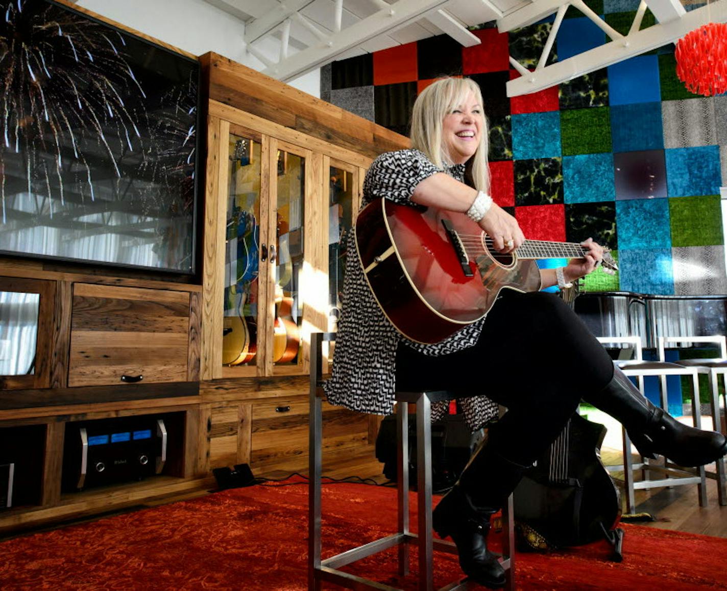 Jan Edwards, a singer/songwriter, strums her guitar on the music room's raised stage.