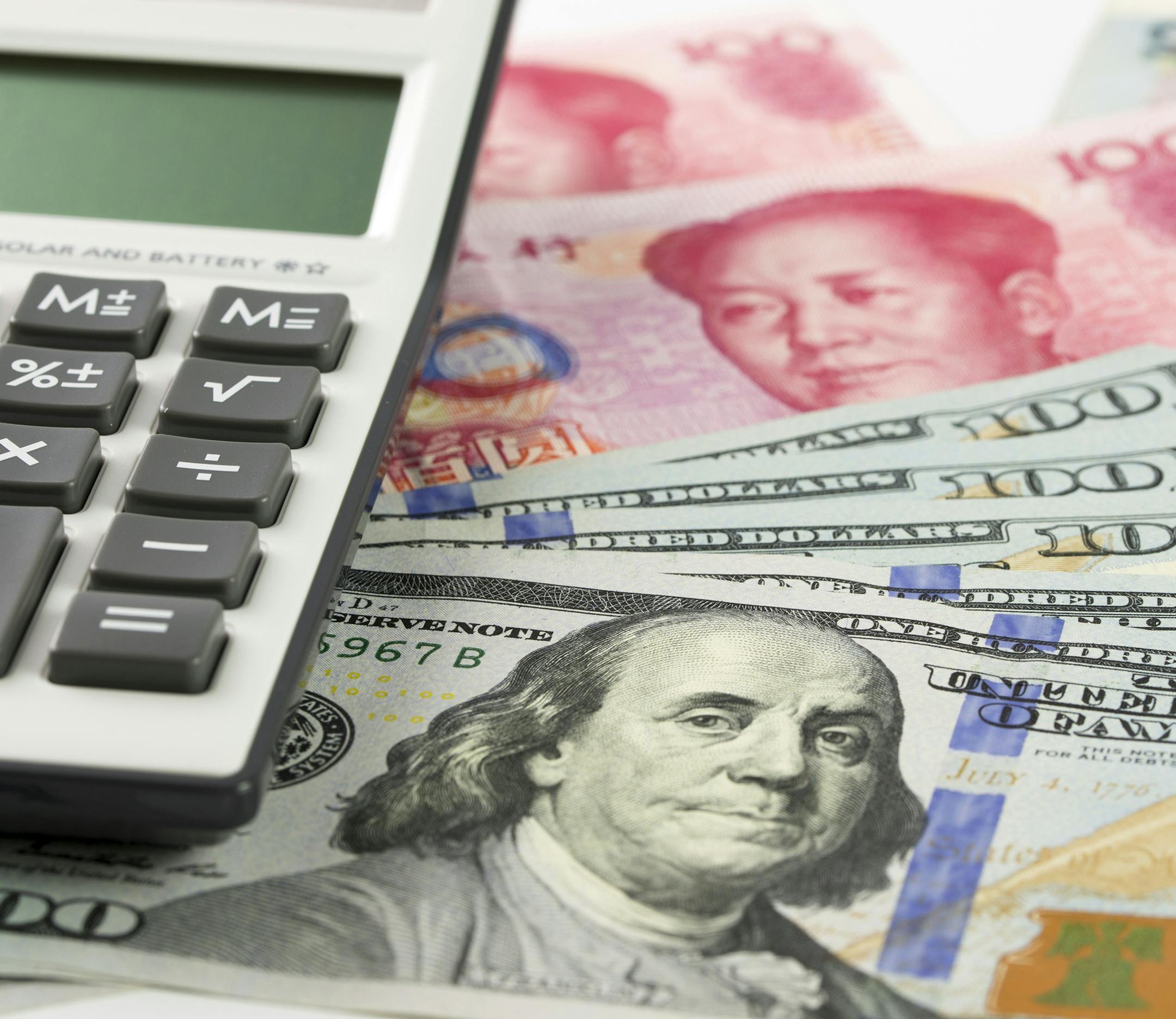 US one hundred dollar and China Yuan bills with calculator