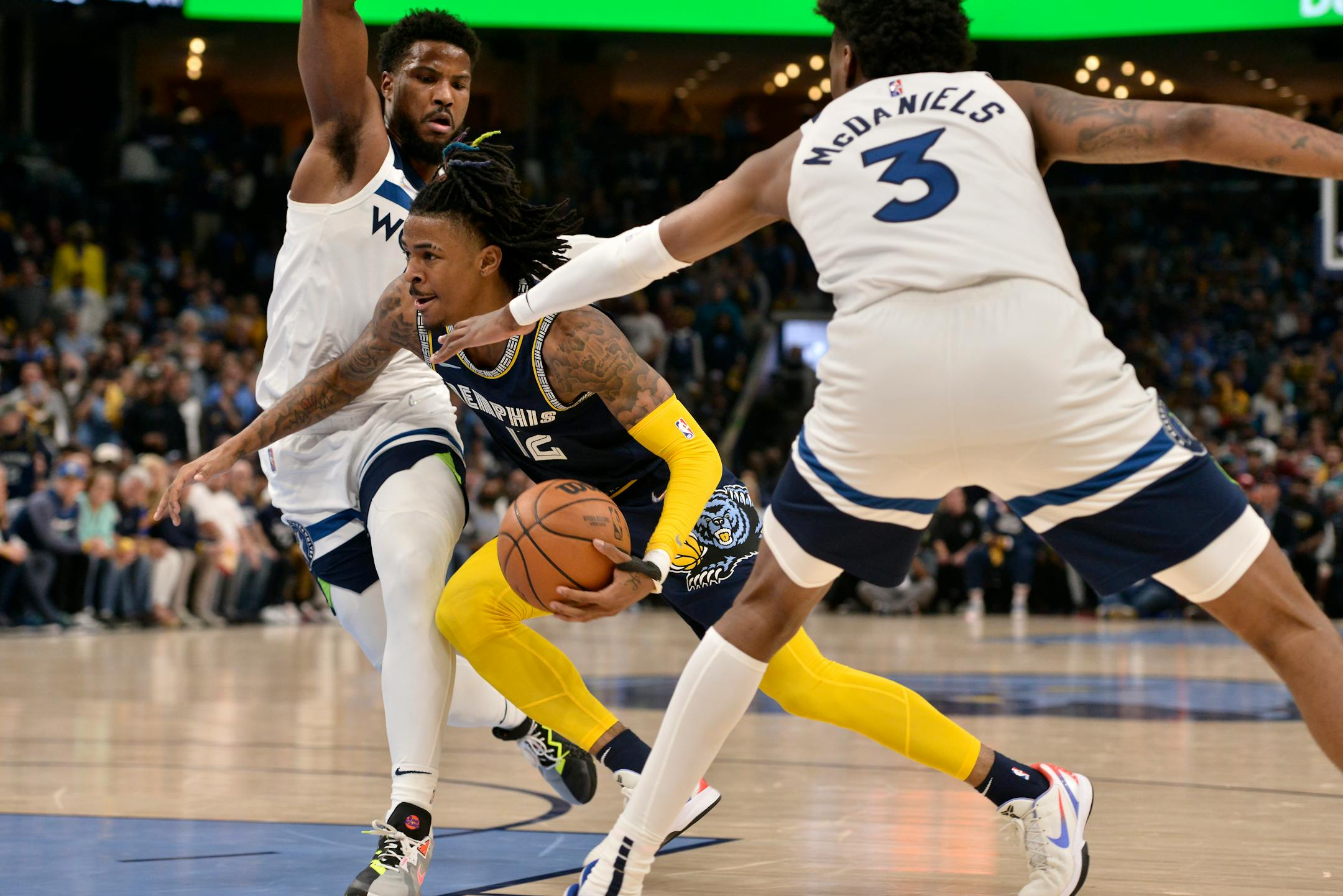 Memphis Grizzlies guard Ja Morant (12) drives between Minnesota Timberwolves forward Jaden McDaniels (3) and guard Malik Beasley (5) during the first half of Game 2 of a first-round NBA basketball playoff series Tuesday, April 19, 2022, in Memphis, Tenn. (AP Photo/Brandon Dill)
