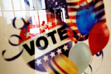 In this Nov. 1, 2016, photo, a voter is reflected in the glass frame of a poster while leaving a polling site in Atlanta, during early voting ahead of