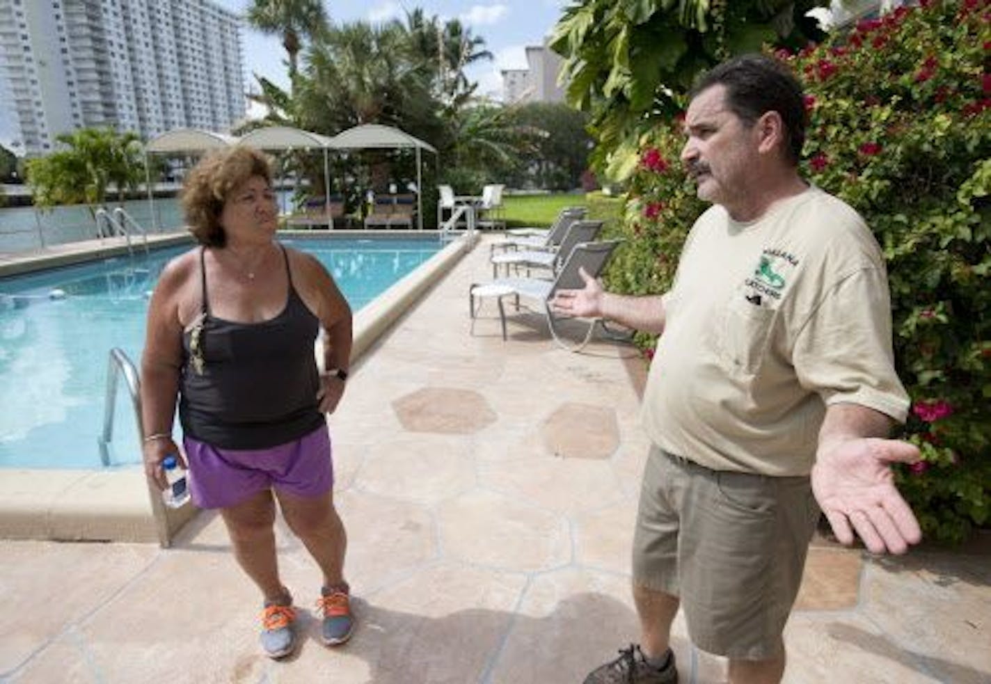 In this Thursday, Feb. 9, 2017 photo, trapper Brian Wood, right, talks with Janet Sarno, board chairwoman at King�s Point Imperial Condo, in Sunny Isles Beach, Fla., about her iguana problem. Sarno hired Wood because the number of iguanas, big adults and bright green babies, hanging around the building�s pool has been growing despite residents� attempts to chase them away or block their entry.