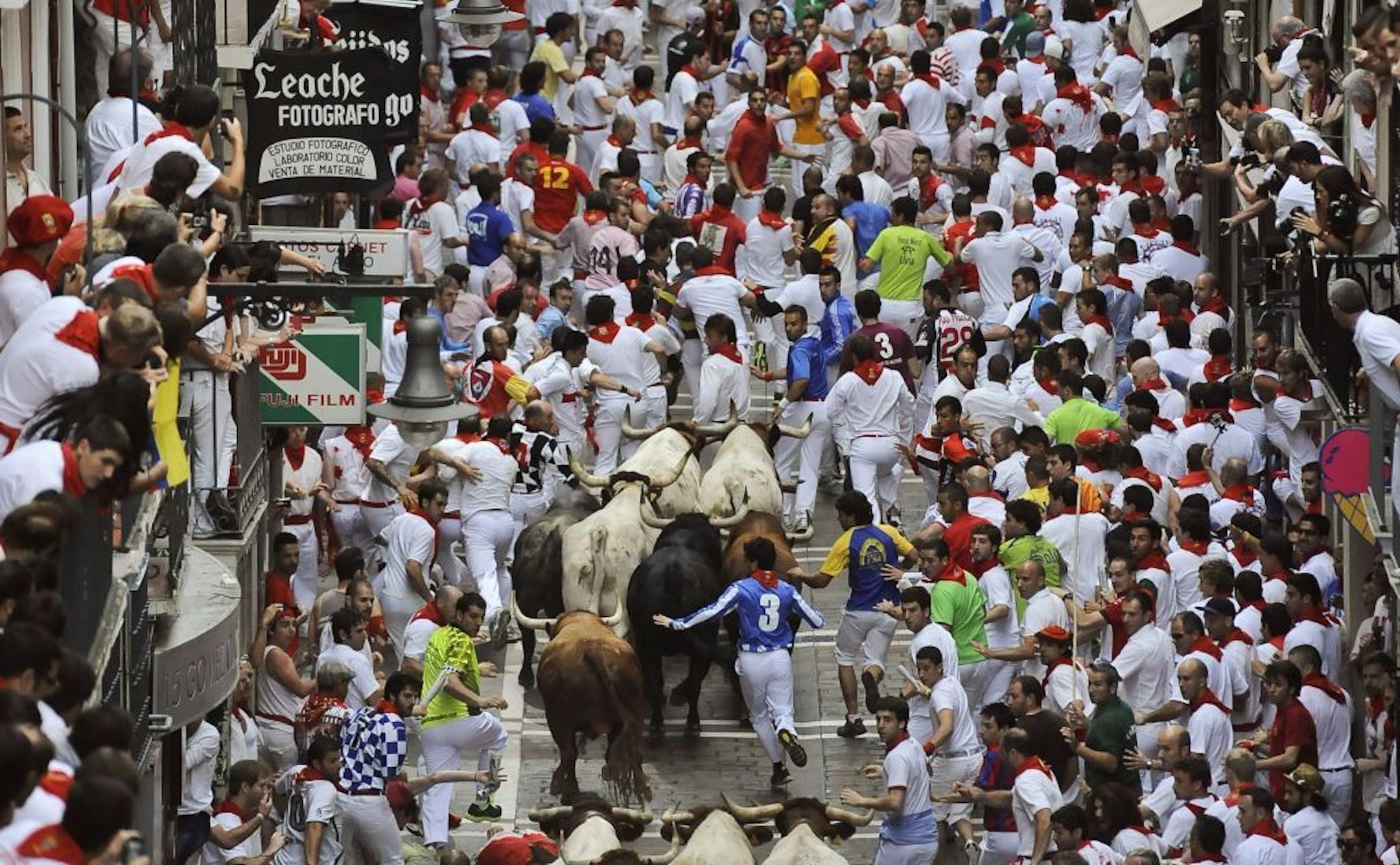 Runners make their way through the street with "El Pilar" fighting bulls watched by people from their balconies during the running of the bulls at the San Fermin festival, in Pamplona, Spain, Friday, July 12, 2013. Revelers from around the world arrive to Pamplona every year to take part in some of the eight days of the running of the bulls.