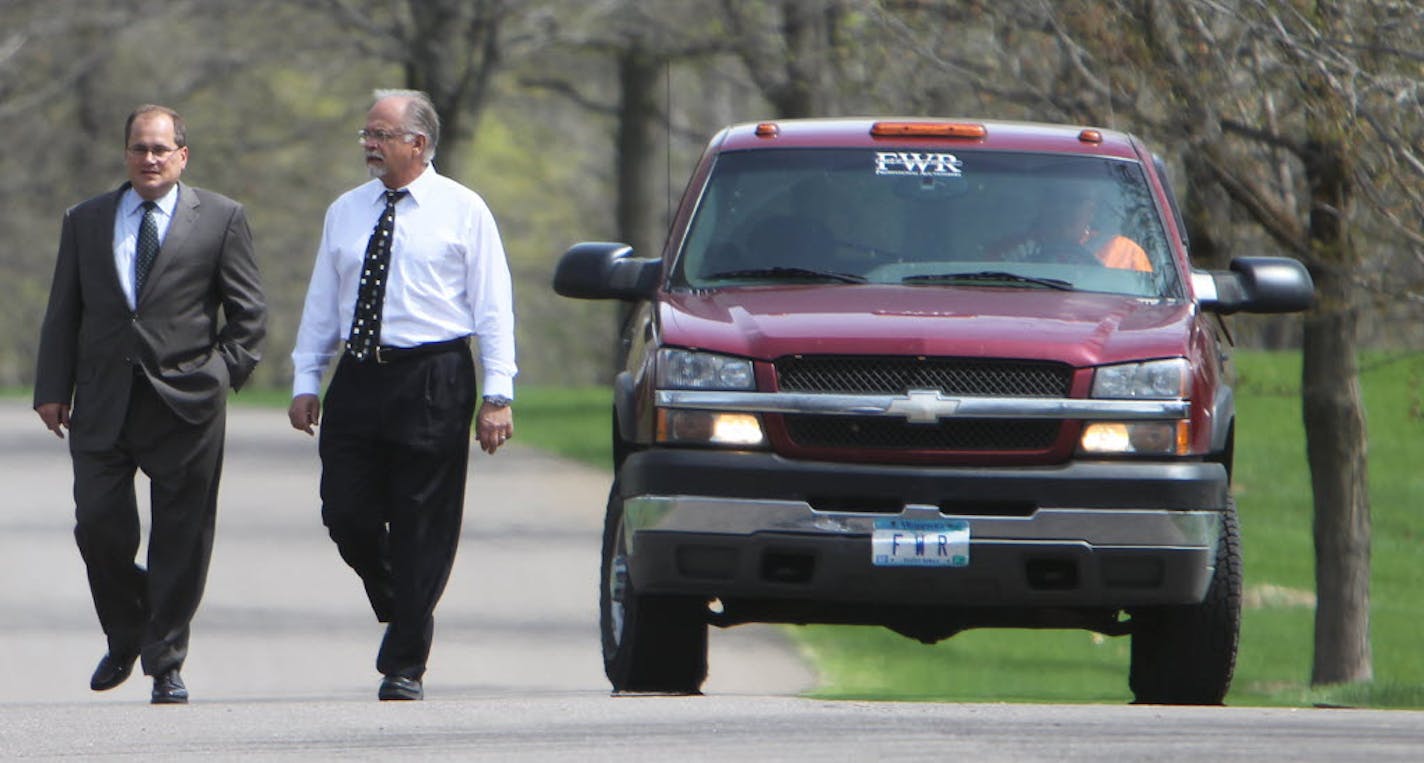 Matthew Burton, attorney for the bankruptcy trustee, and Brian N. Toder, Hecker's attorney, walk down to talk to the media while a truck from the Fred W. Radde & Sons auction house leaves Denny Hecker's house in Medina.