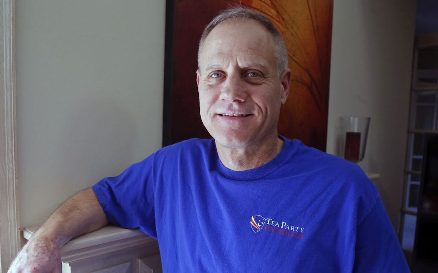 In this Feb. 16, 2018, photo, Andy Cilek poses with a Tea Party shirt at his home in Eden Prairie, Minn. Cilek was one of two voters who defied elections officials after he was asked to cover up a tea-party shirt and button. A Minnesota law that bars voters from wearing political hats, T-shirts, buttons and other apparel to the polls is about to get a look from the Supreme Court.