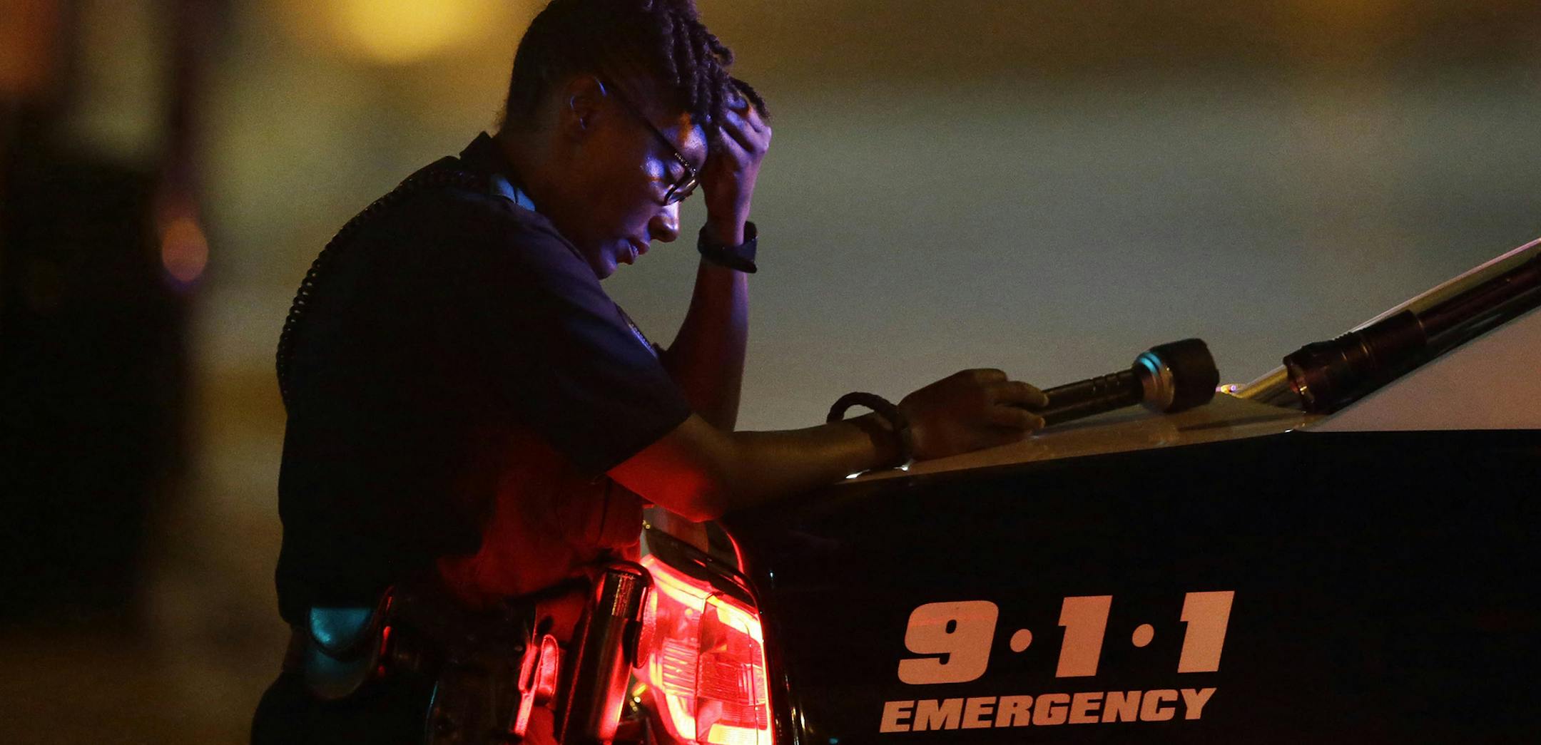 A Dallas police officer, who did not want to be identified, takes a moment as she guards an intersection in the early morning after a shooting in downtown Dallas, Friday, July 8, 2016. At least two snipers opened fire on police officers during protests in Dallas on Thursday night; some of the officers were killed, police said. (AP Photo/LM Otero) ORG XMIT: MIN2016070811540020