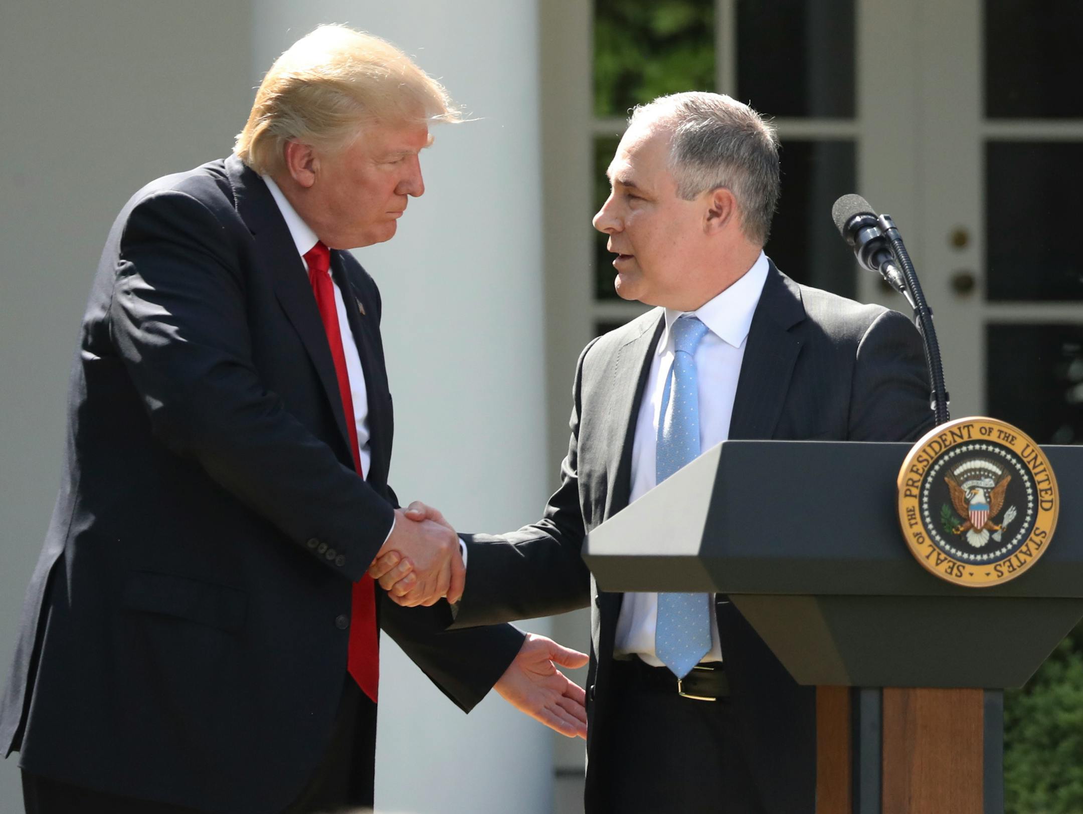 FILE - In this June 1, 2017 file photo, President Donald Trump shakes hands with EPA Administrator Scott Pruitt after speaking about the U.S. role in the Paris climate change accord in the Rose Garden of the White House in Washington. A new poll finds that less than a third of Americans support President Donald Trump�s decision to withdraw from the Paris climate accord, with just 18 percent of respondents agreeing with his claim that pulling out of the international agreement to reduce carbon em