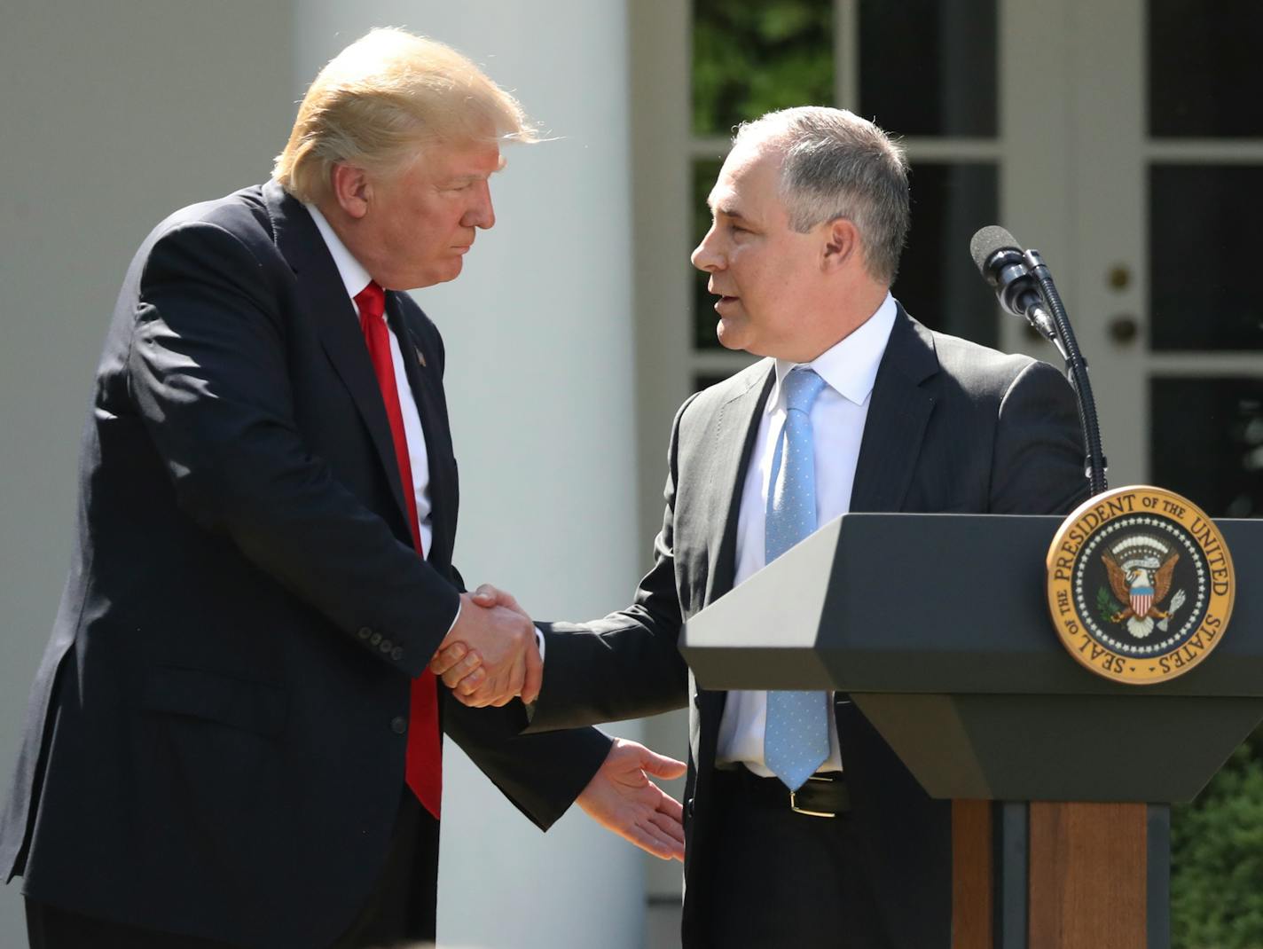 FILE - In this June 1, 2017 file photo, President Donald Trump shakes hands with EPA Administrator Scott Pruitt after speaking about the U.S. role in the Paris climate change accord in the Rose Garden of the White House in Washington. A new poll finds that less than a third of Americans support President Donald Trump�s decision to withdraw from the Paris climate accord, with just 18 percent of respondents agreeing with his claim that pulling out of the international agreement to reduce carbon em