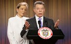 Colombia's President Juan Manuel Santos speaks to the press under the look of his wife Maria Clemencia Rodriguez at the presidential palace in Bogota,