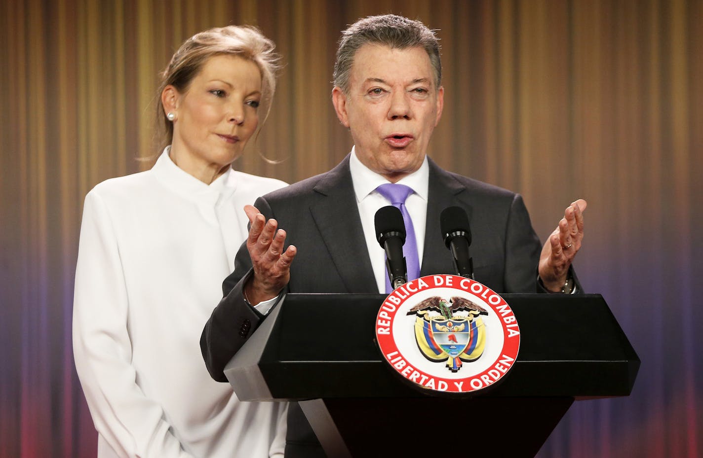 Colombia's President Juan Manuel Santos speaks to the press under the look of his wife Maria Clemencia Rodriguez at the presidential palace in Bogota, Colombia, Friday, Oct. 7, 2016. Colombian President Juan Manuel Santos won the Nobel Peace Prize Friday, just days after voters narrowly rejected a peace deal he signed with rebels of the Revolutionary Armed Forces of Colombia, FARC. (AP Photo/Fernando Vergara) ORG XMIT: MIN2016101112220917