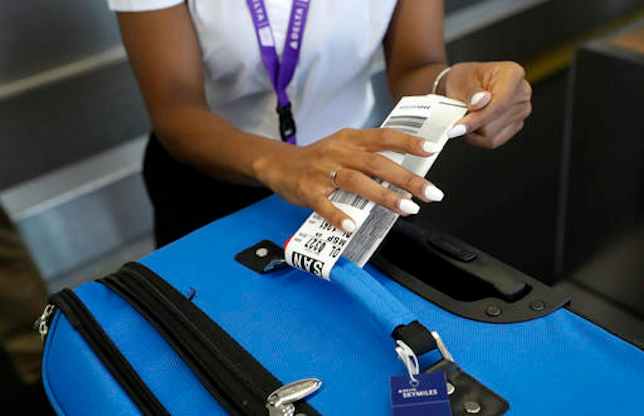 In this July 12, 2016, photo, Delta Air Lines employee Helen Evans places an RFID-enabled baggage tag on a passenger's checked bag at Baltimore-Washington International Thurgood Marshall Airport in Linthicum, Md. Delta Air Lines is rolling out new technology to better track bags throughout its system. (AP Photo/Patrick Semansky)
