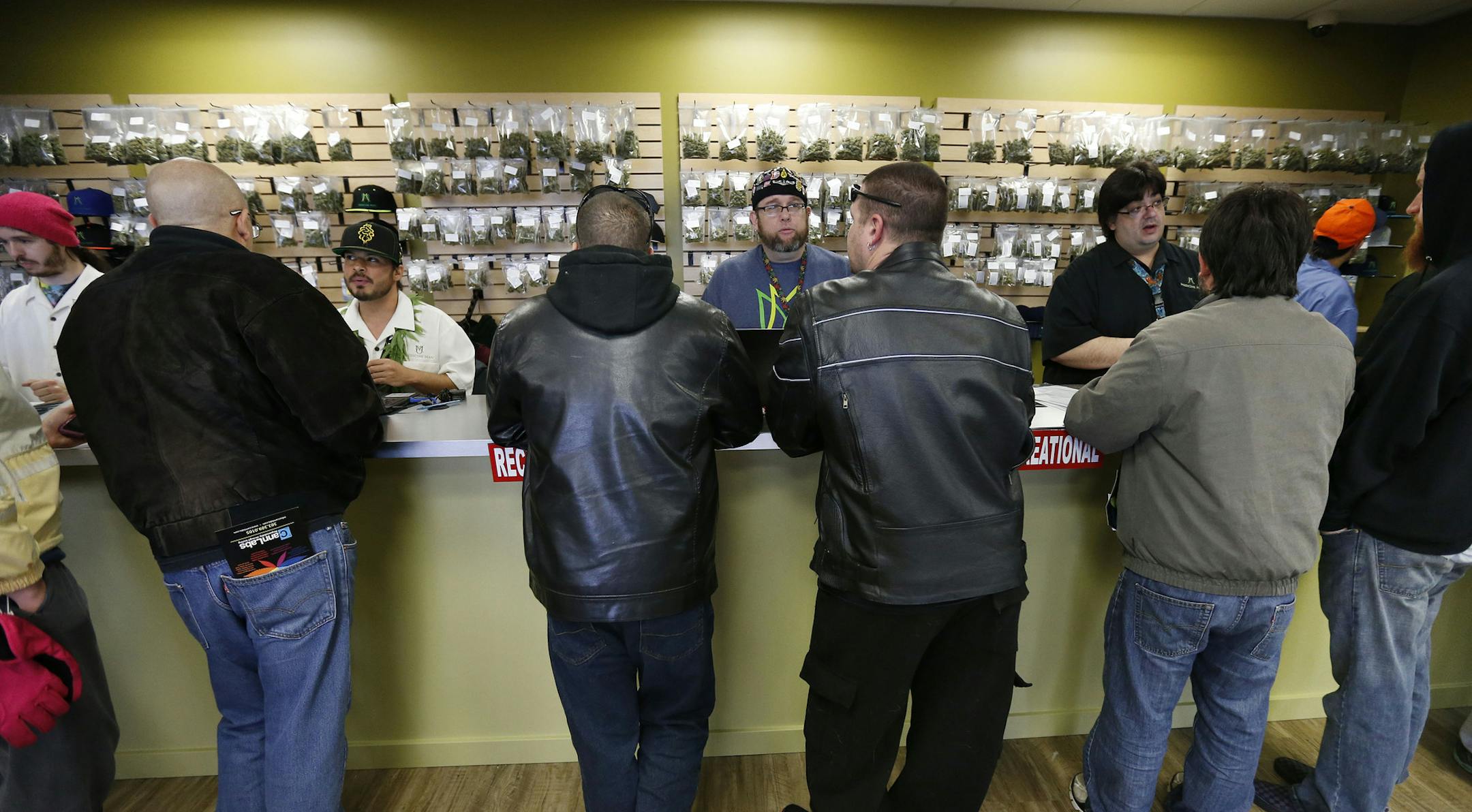FILE - In this Jan. 1, 2014 file photo, employees help customers at the crowded sales counter inside the Medicine Man marijuana retail store, in Denver. A group of marijuana activists want another pot vote in Colorado, to loosen restrictions on who can have it. A proposed ballot measure up for state review Wednesday Jan. 14, 2014 would end criminal penalties for cannabis possession. If approved, the measure would effectively discard Colorado&#xed;s 1-ounce possession limit and 21-and-over restri
