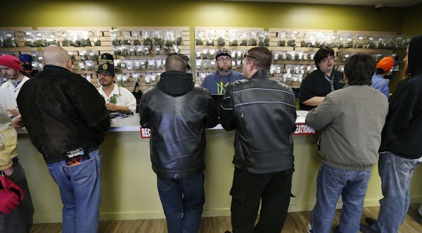 FILE - In this Jan. 1, 2014 file photo, employees help customers at the crowded sales counter inside the Medicine Man marijuana retail store, in Denve