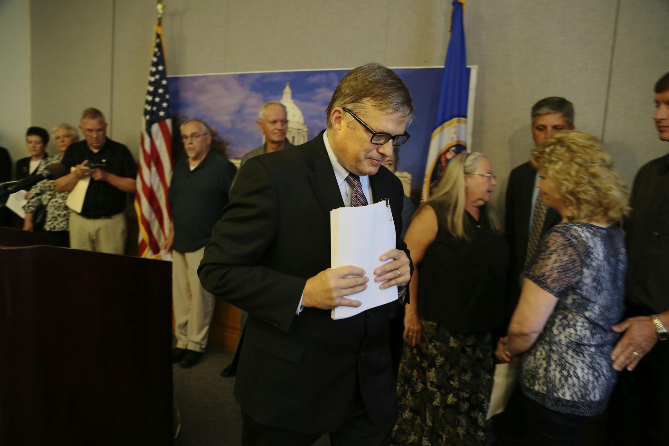 After initially briefing media members attorney, Erick Kaardal of Mohrman & Kaardal walks away from the podium cluthing the 95 page federal lawsuit as many of the suit's plaintiffs stood to the rear Thursday, Sept 12, 2013, at the State Capitol, in St. Paul, MN.