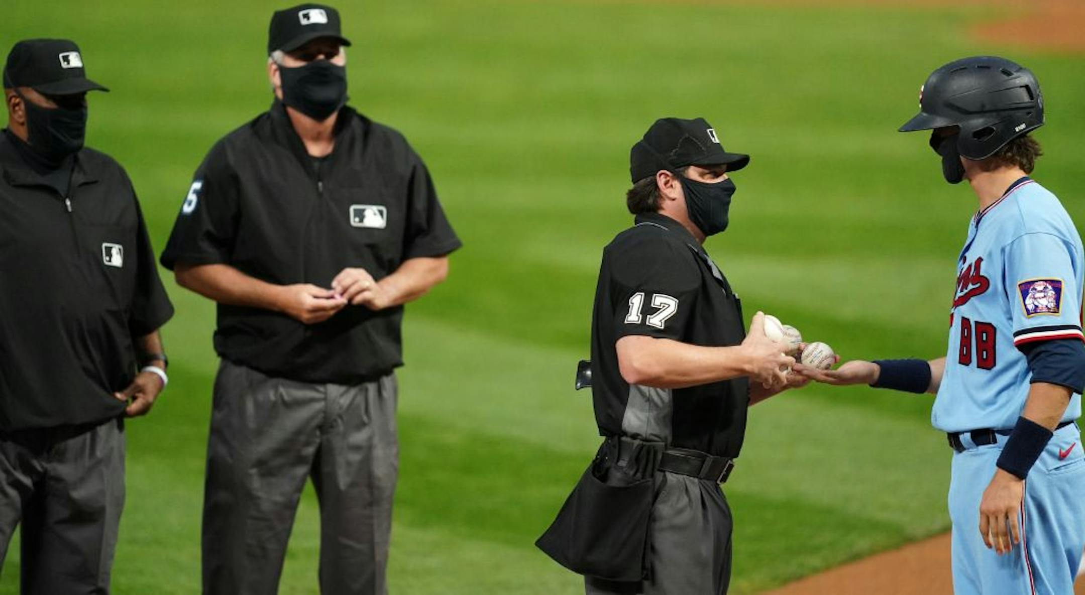 MLB umpire D.J. Reyburn (17) got handed new baseballs by the Minnesota Twins bat boy ahead of Saturday's game.