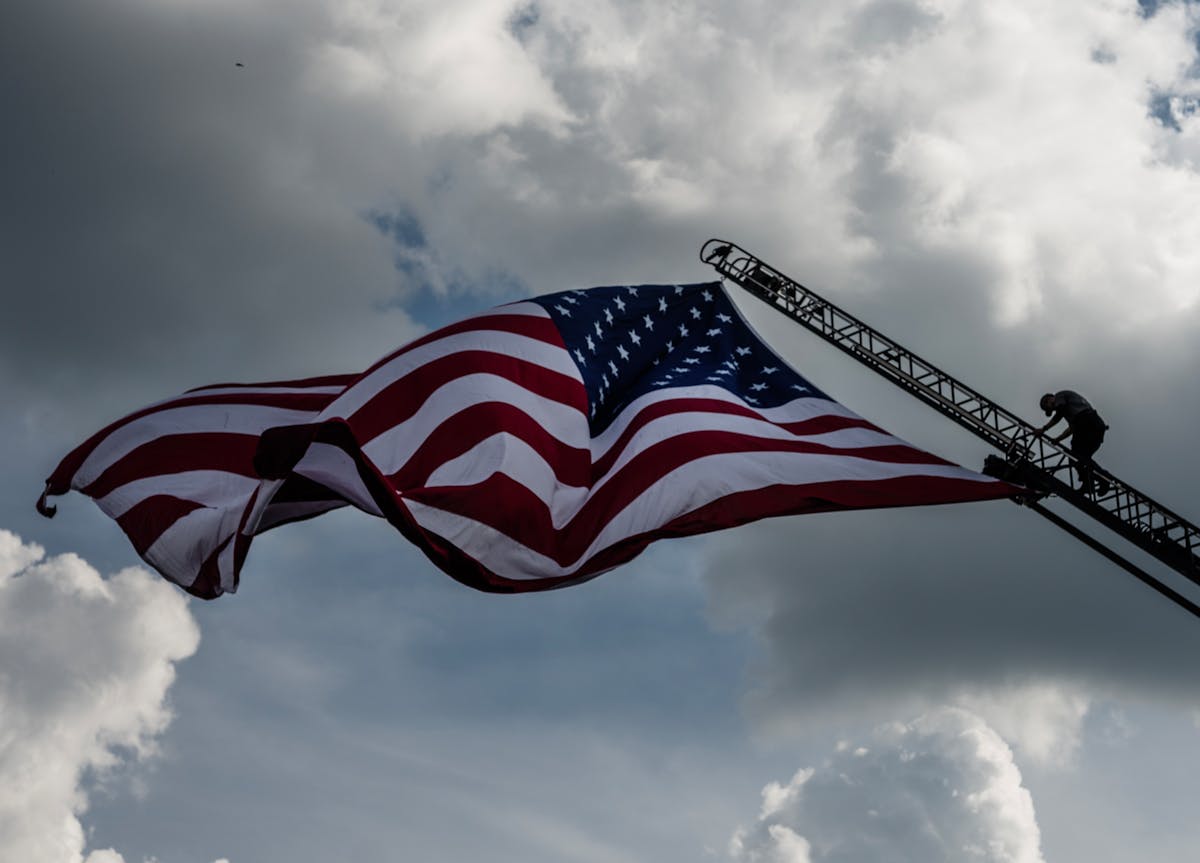 Jake Gruber of the Bloomington Police Department climbs up about 100 feet in the air to where American Flag hangs from a city fire ladder truck in Blo