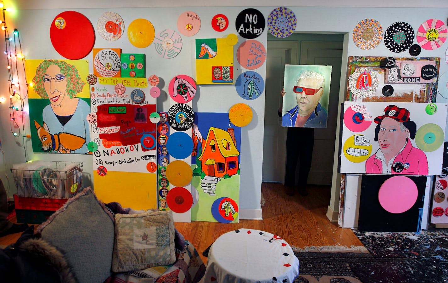 Inside the home of artist Frank Gaard, Pam Gaard holds a portrait she did of Frank.