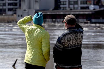 Pedestrians came out to view the flooding at Harriet Island Regional Park and the flowing Mississippi River in St. Paul on Monday afternoon.