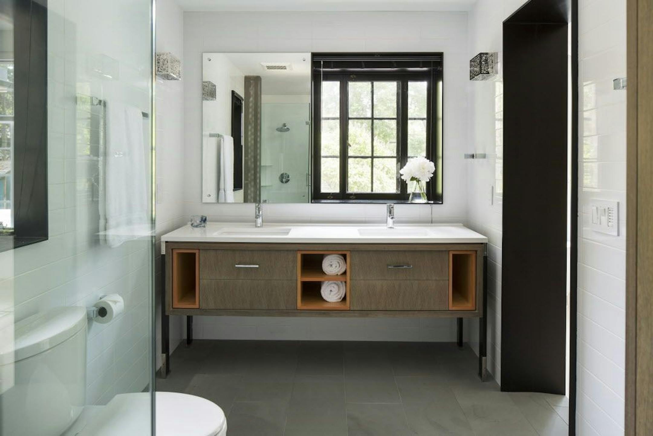 The spa-style bathroom features a heated bluestone floor, glass-enclosed shower, double sinks and plenty of storage cabinets.
