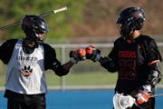 Twin brothers Dayton, left, and Dante Buck fist-bumped before a lacrosse game against Eastview High School Thursday.