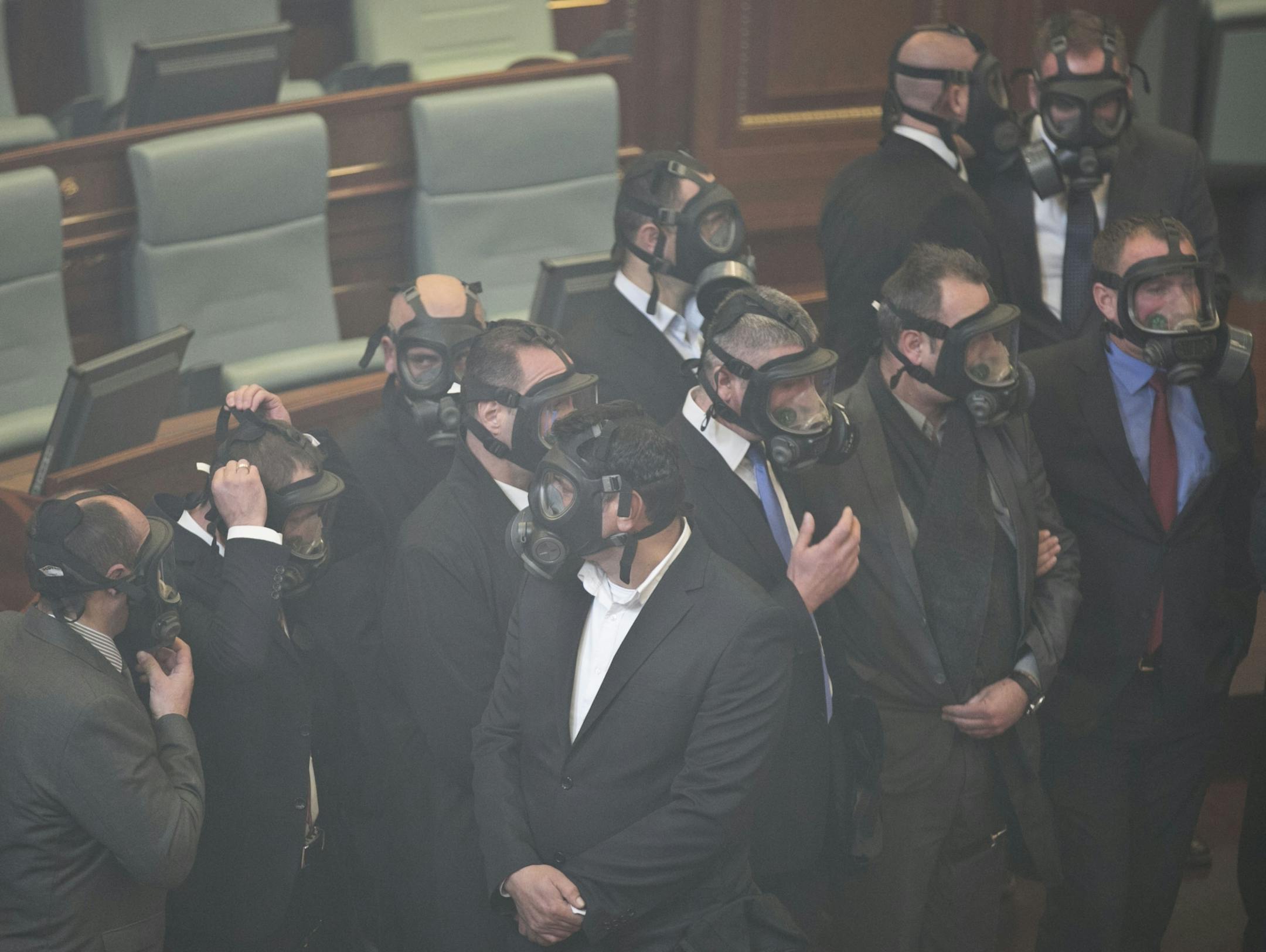 Kosovo parliament security wear gas masks after opposition lawmakers released a tear gas canister disrupting a parliamentary session in Kosovo capital Pristina on Monday Dec. 14, 2015. Opposition lawmakers have released tear gas in Kosovo�s parliament in their latest attempt to pressure the government into renouncing deals with Serbia and Montenegro.